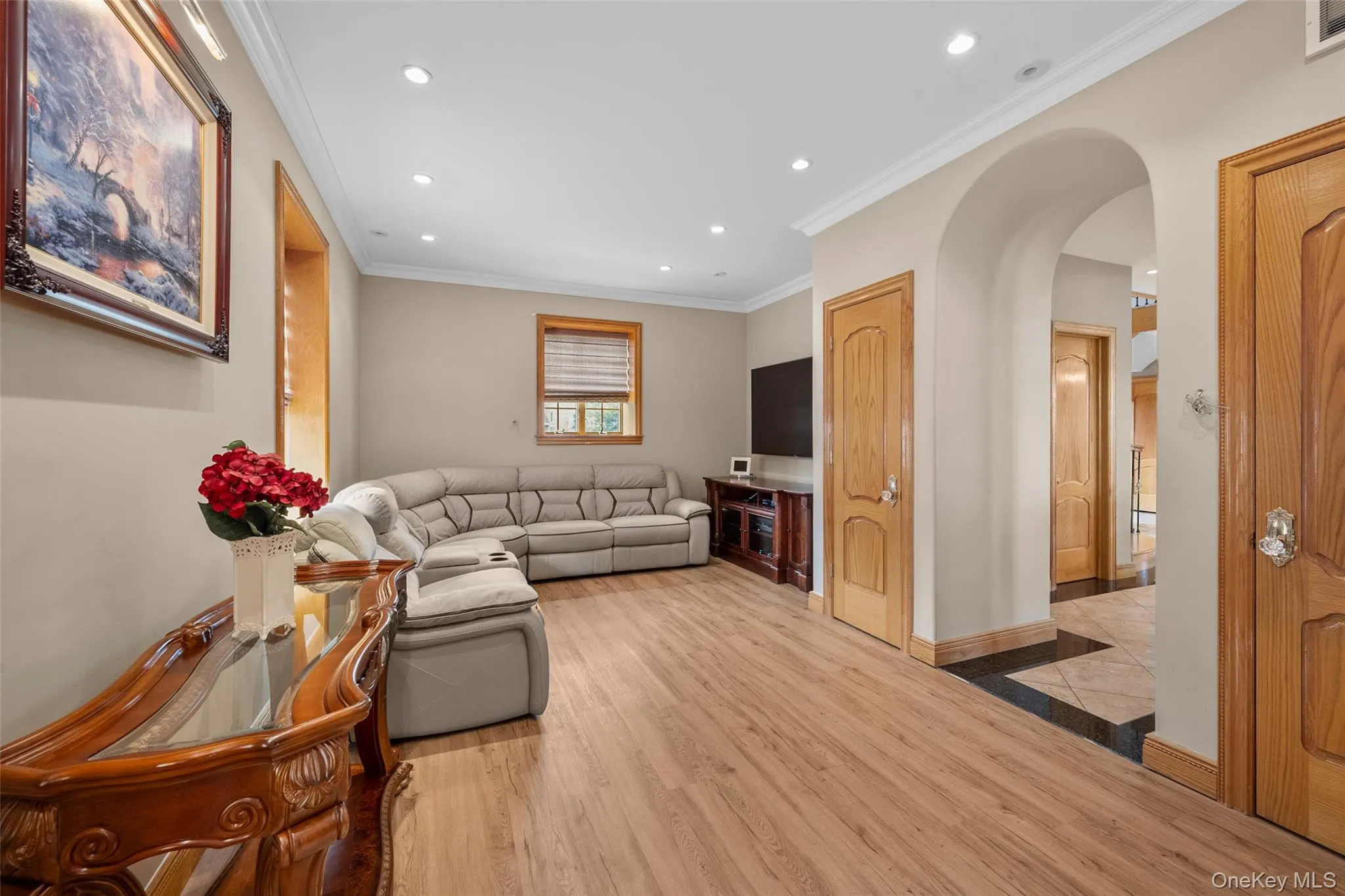 Living room with visible vents, ornamental molding, light wood-style flooring, recessed lighting, and arched walkways Living room with visible vents, ornamental molding, light wood-style flooring, recessed lighting, and arched walkways