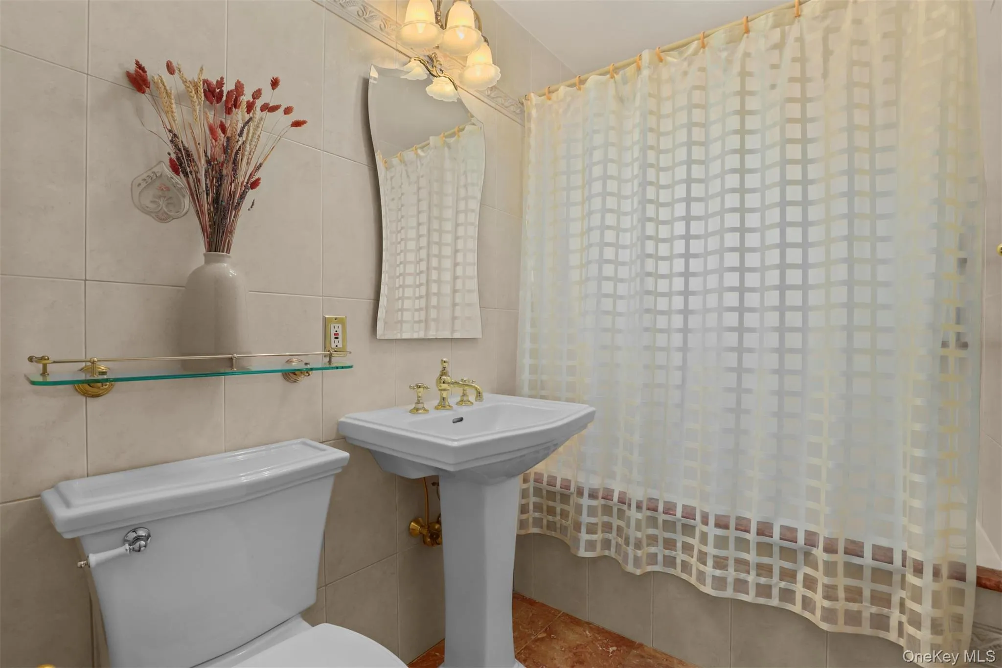 Bathroom featuring a sink, toilet, tile walls, and tile patterned flooring Bathroom featuring a sink, toilet, tile walls, and tile patterned flooring