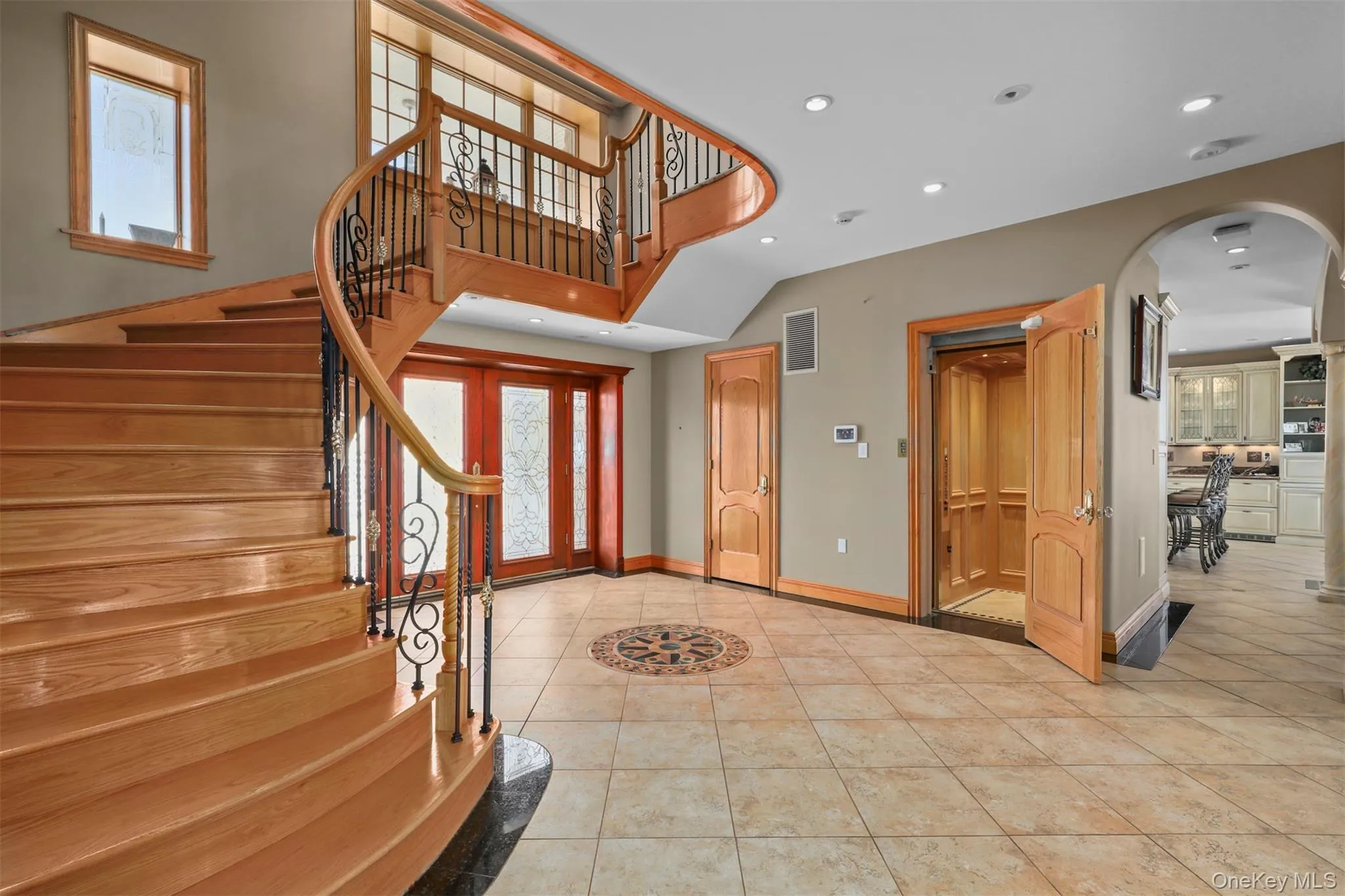 Foyer entrance with visible vents, arched walkways, stairs, and tile patterned flooring Foyer entrance with visible vents, arched walkways, stairs, and tile patterned flooring