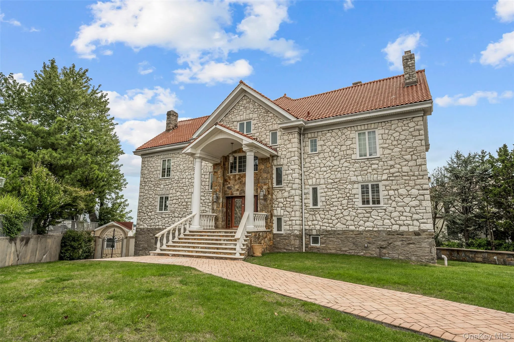 View of front of property featuring stone siding, a chimney, a front lawn, and a tile roof View of front of property featuring stone siding, a chimney, a front lawn, and a tile roof