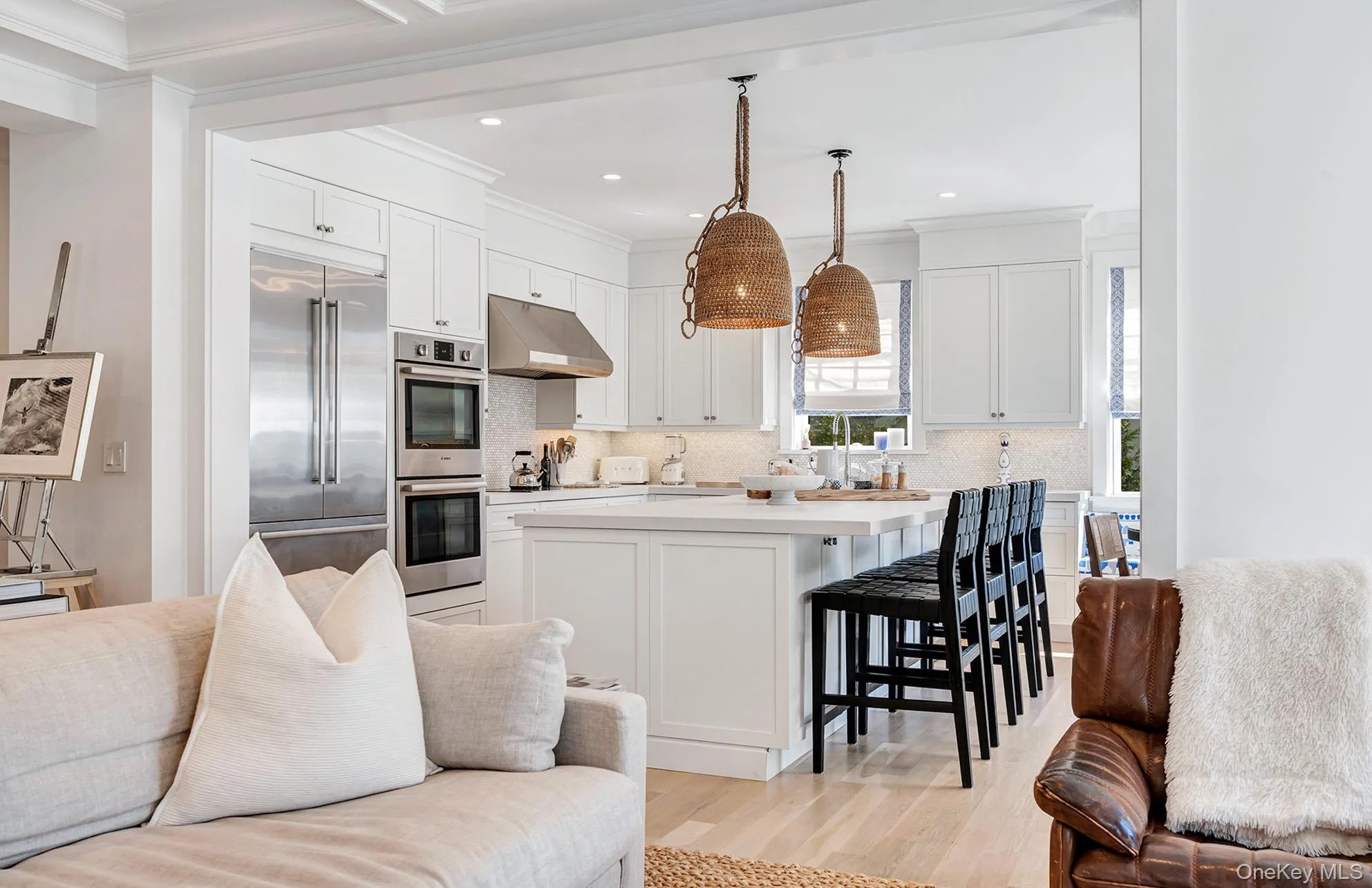 Kitchen with decorative light fixtures, tasteful backsplash, white cabinets, light hardwood / wood-style floors, and stainless steel appliances Kitchen with decorative light fixtures, tasteful backsplash, white cabinets, light hardwood / wood-style floors, and stainless steel appliances