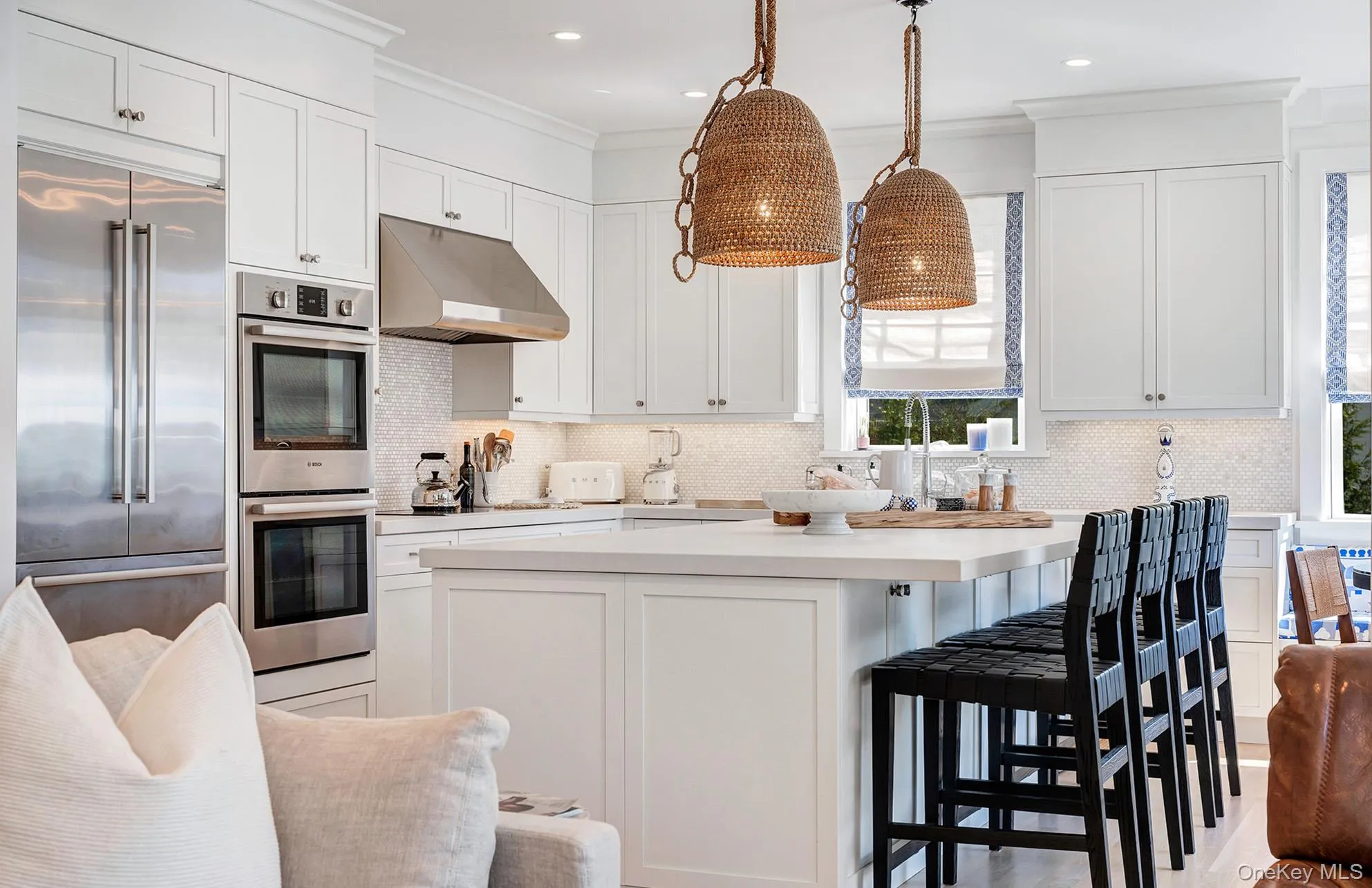 Kitchen featuring hanging light fixtures, white cabinetry, backsplash, and stainless steel appliances Kitchen featuring hanging light fixtures, white cabinetry, backsplash, and stainless steel appliances