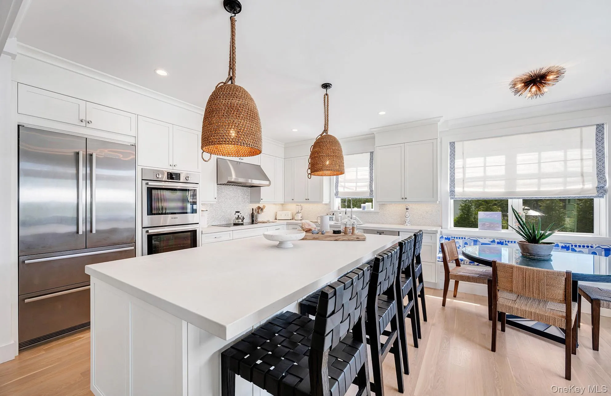 Kitchen featuring a kitchen island, appliances with stainless steel finishes, decorative light fixtures, white cabinetry, and a kitchen breakfast bar Kitchen featuring a kitchen island, appliances with stainless steel finishes, decorative light fixtures, white cabinetry, and a kitchen breakfast bar