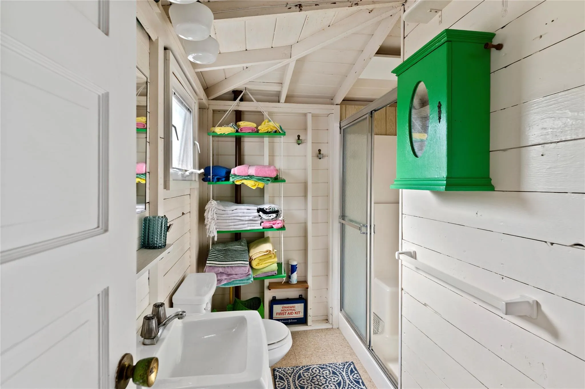 Bathroom featuring toilet, sink, wooden ceiling, wooden walls, and a shower with door Bathroom featuring toilet, sink, wooden ceiling, wooden walls, and a shower with door