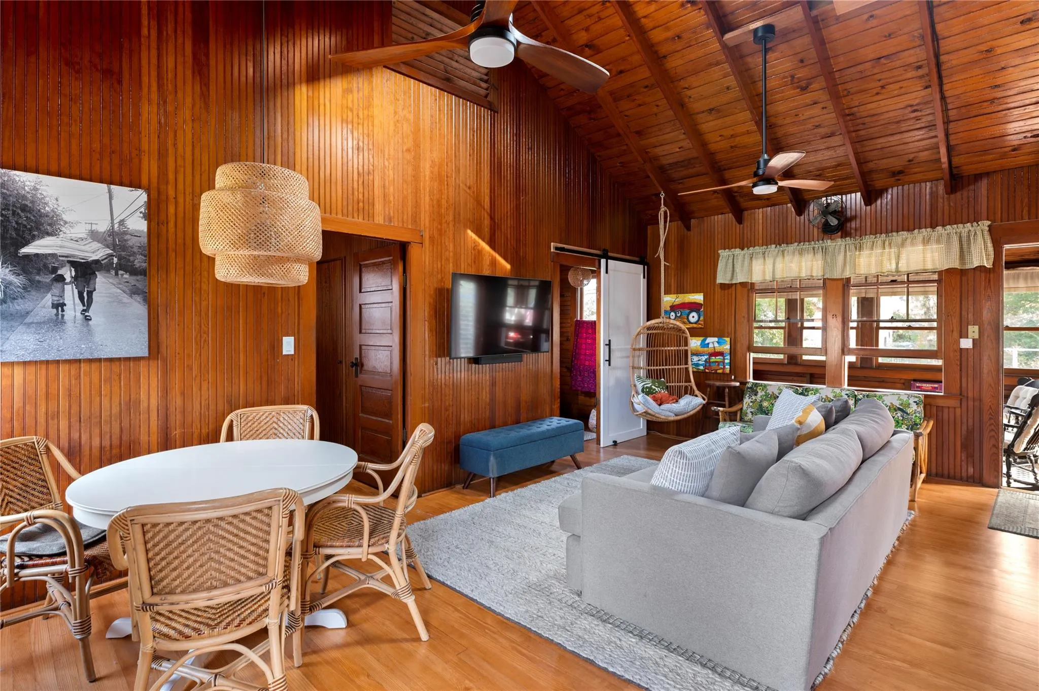 Living room featuring beam ceiling, wooden walls, wooden ceiling, and a barn door Living room featuring beam ceiling, wooden walls, wooden ceiling, and a barn door