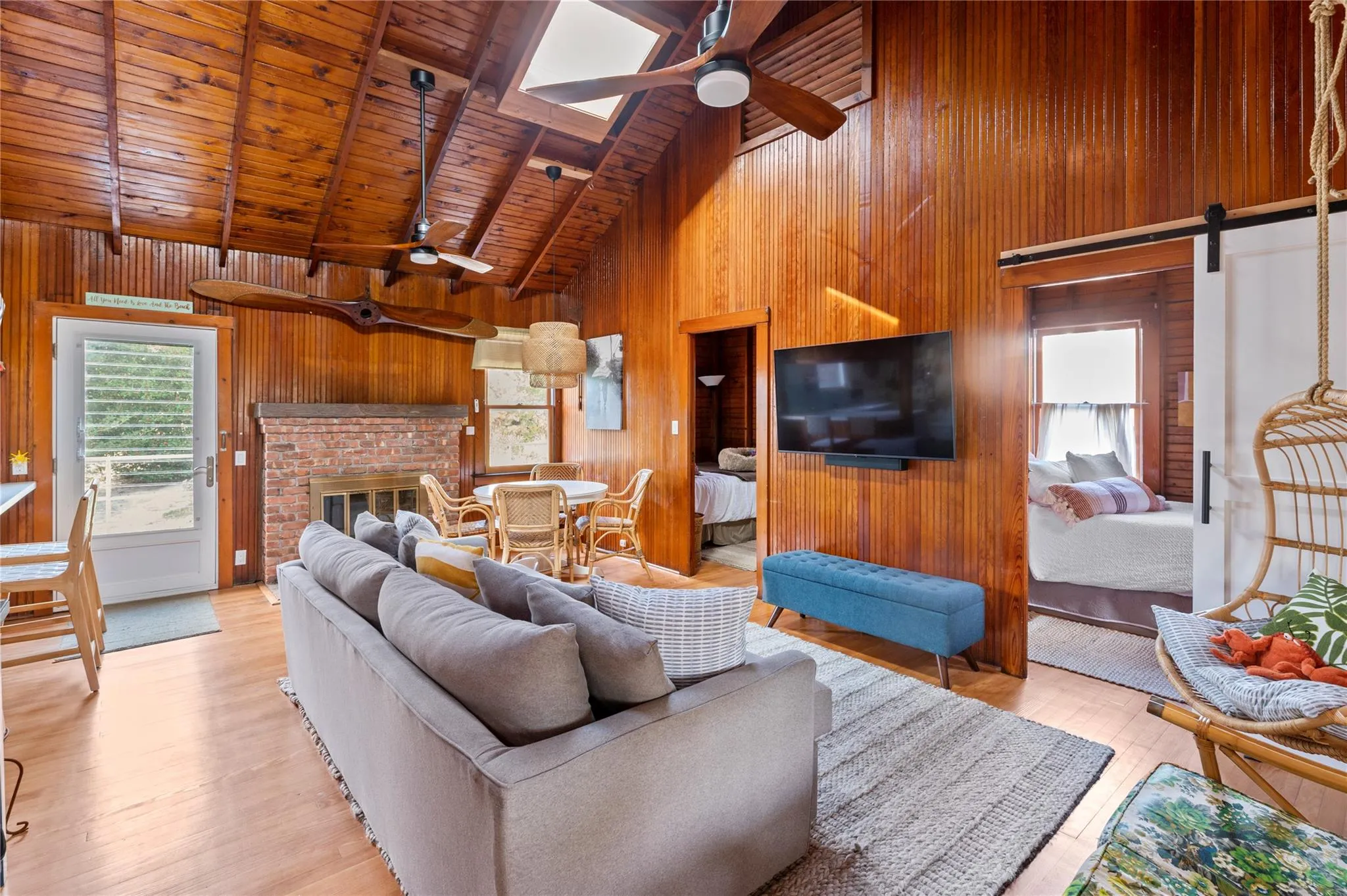 Living room with beamed ceiling, a barn door, wooden ceiling, and wood walls Living room with beamed ceiling, a barn door, wooden ceiling, and wood walls