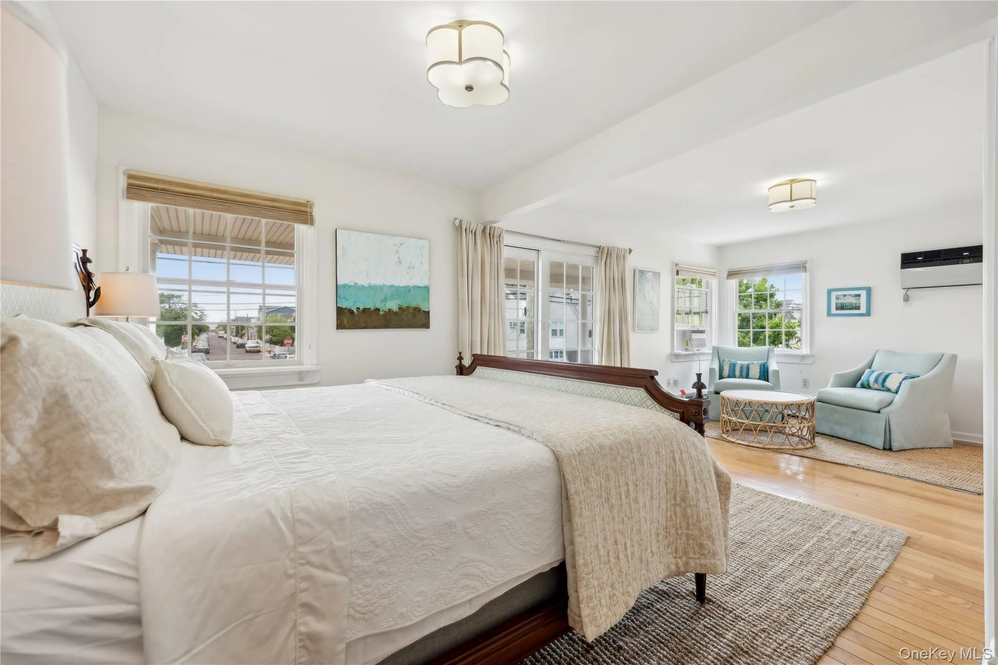 Bedroom featuring multiple windows, a wall mounted air conditioner, and hardwood / wood-style floors Bedroom featuring multiple windows, a wall mounted air conditioner, and hardwood / wood-style floors