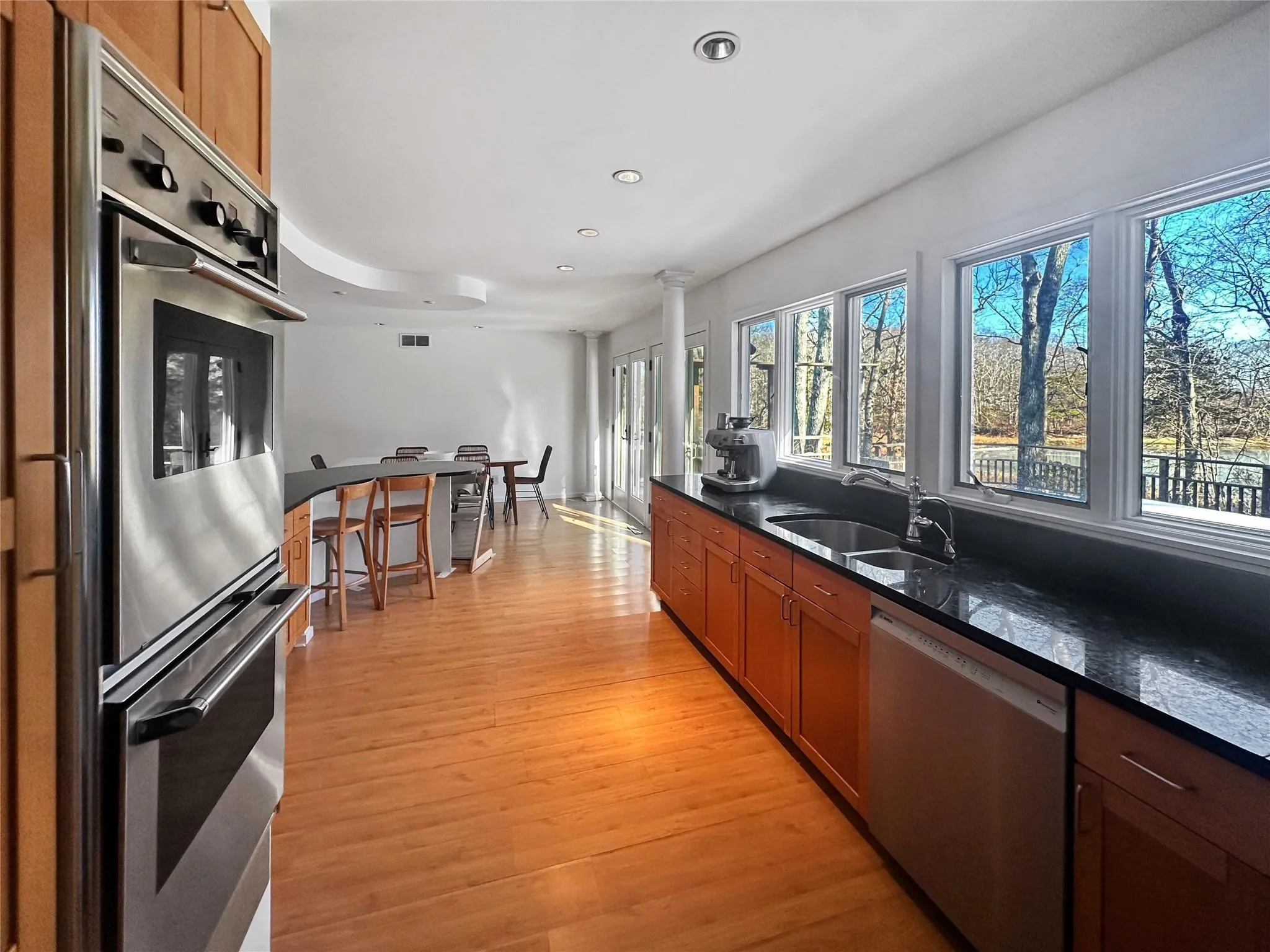 Kitchen with sink, light hardwood / wood-style flooring, white dishwasher, dark stone counters, and stainless steel double oven Kitchen with sink, light hardwood / wood-style flooring, white dishwasher, dark stone counters, and stainless steel double oven