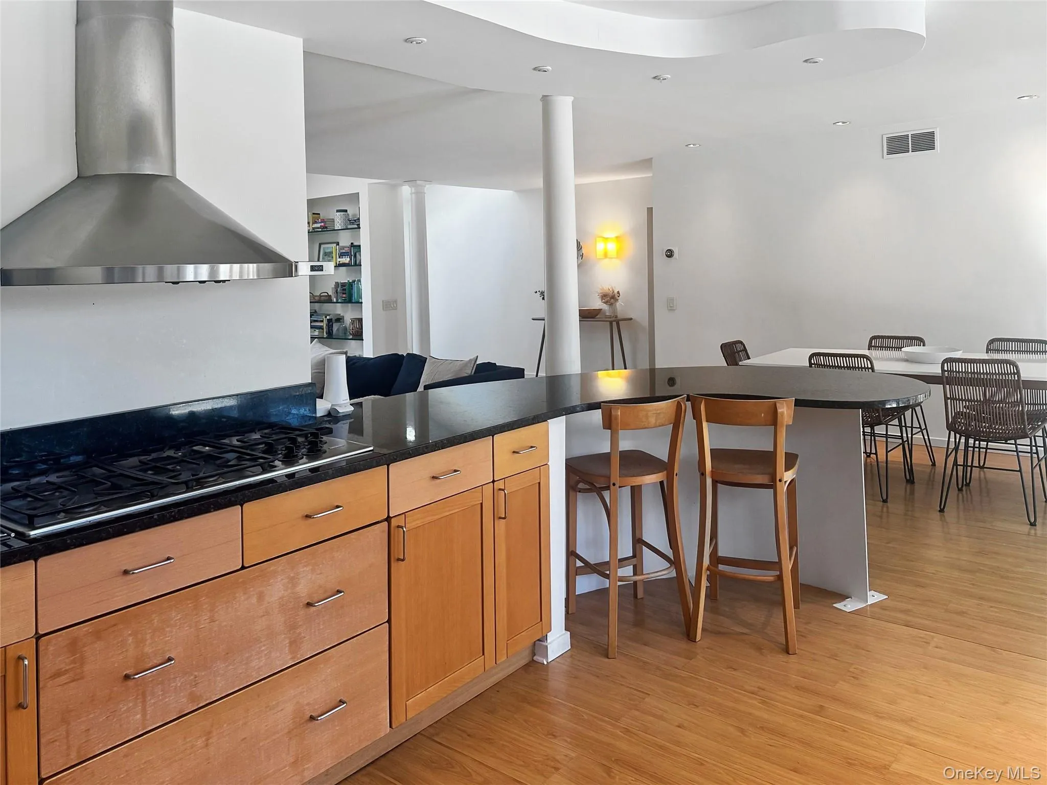 Kitchen with ornate columns, extractor fan, black gas cooktop, a breakfast bar area, and light hardwood / wood-style floors Kitchen with ornate columns, extractor fan, black gas cooktop, a breakfast bar area, and light hardwood / wood-style floors