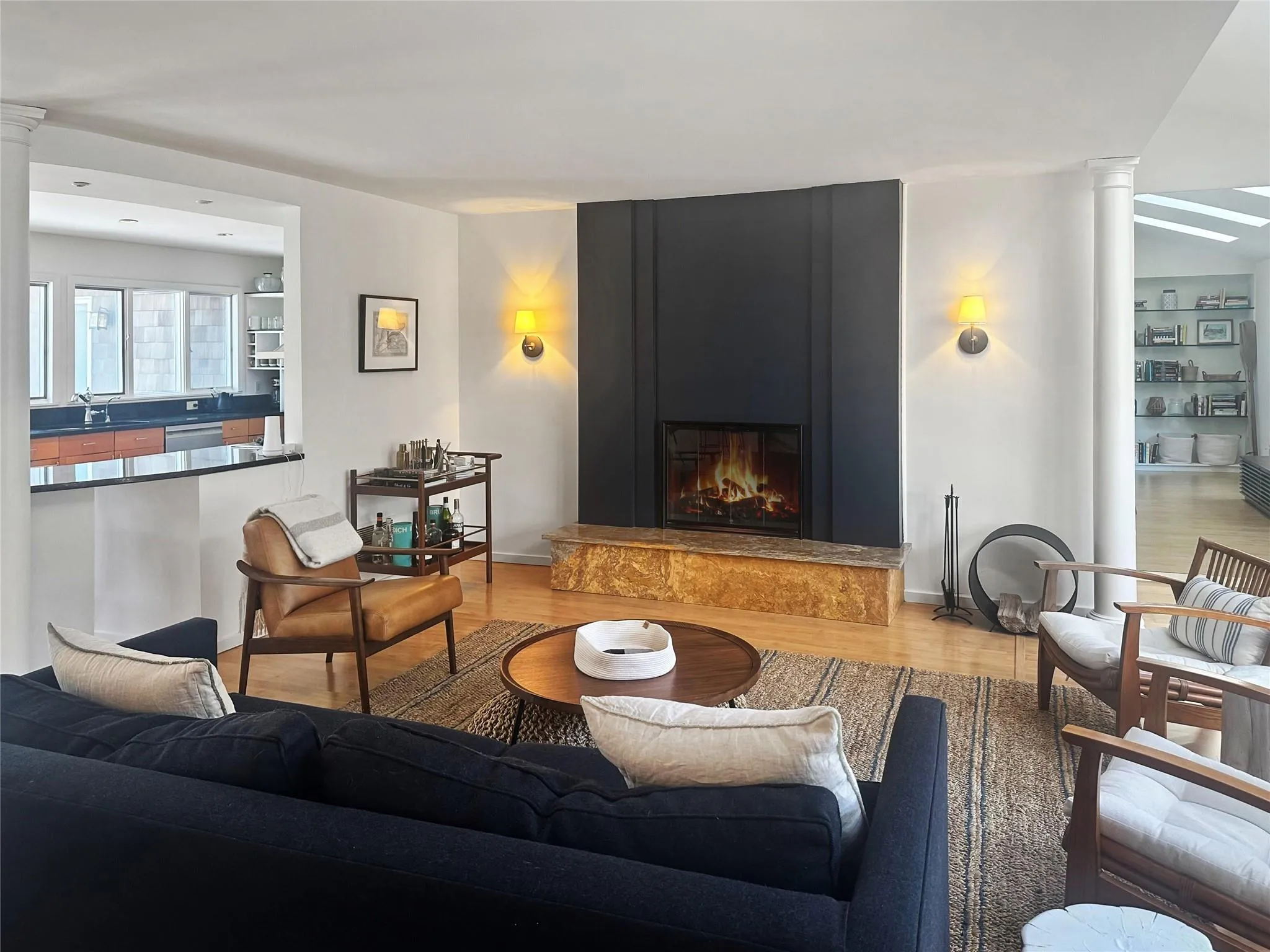 Living room with decorative columns, a premium fireplace, hardwood / wood-style flooring, and sink Living room with decorative columns, a premium fireplace, hardwood / wood-style flooring, and sink