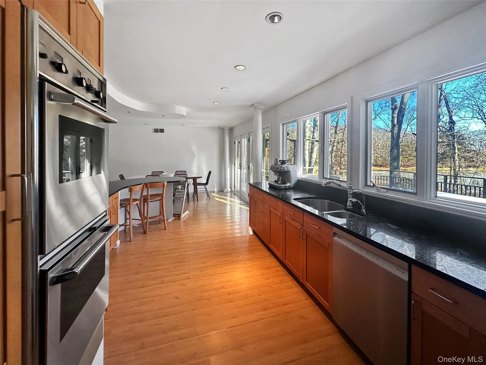 Kitchen with sink, light hardwood / wood-style flooring, white dishwasher, dark stone counters, and stainless steel double oven Kitchen with sink, light hardwood / wood-style flooring, white dishwasher, dark stone counters, and stainless steel double oven