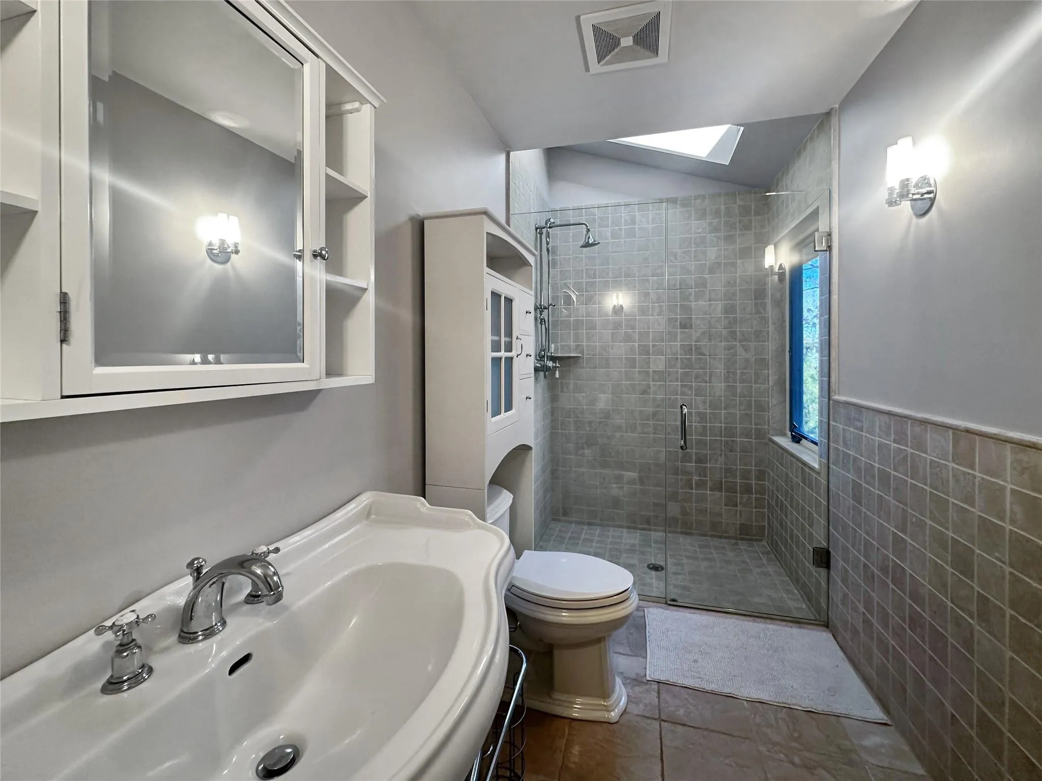 Bathroom with sink, tile walls, toilet, a shower with door, and tile patterned floors Bathroom with sink, tile walls, toilet, a shower with door, and tile patterned floors