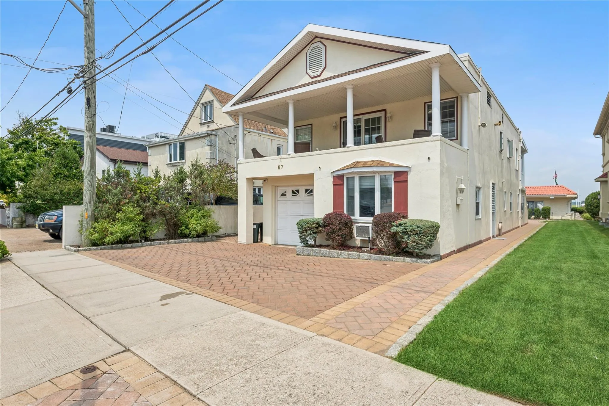 View of front of property featuring cooling unit, a garage, a front lawn, and a balcony View of front of property featuring cooling unit, a garage, a front lawn, and a balcony
