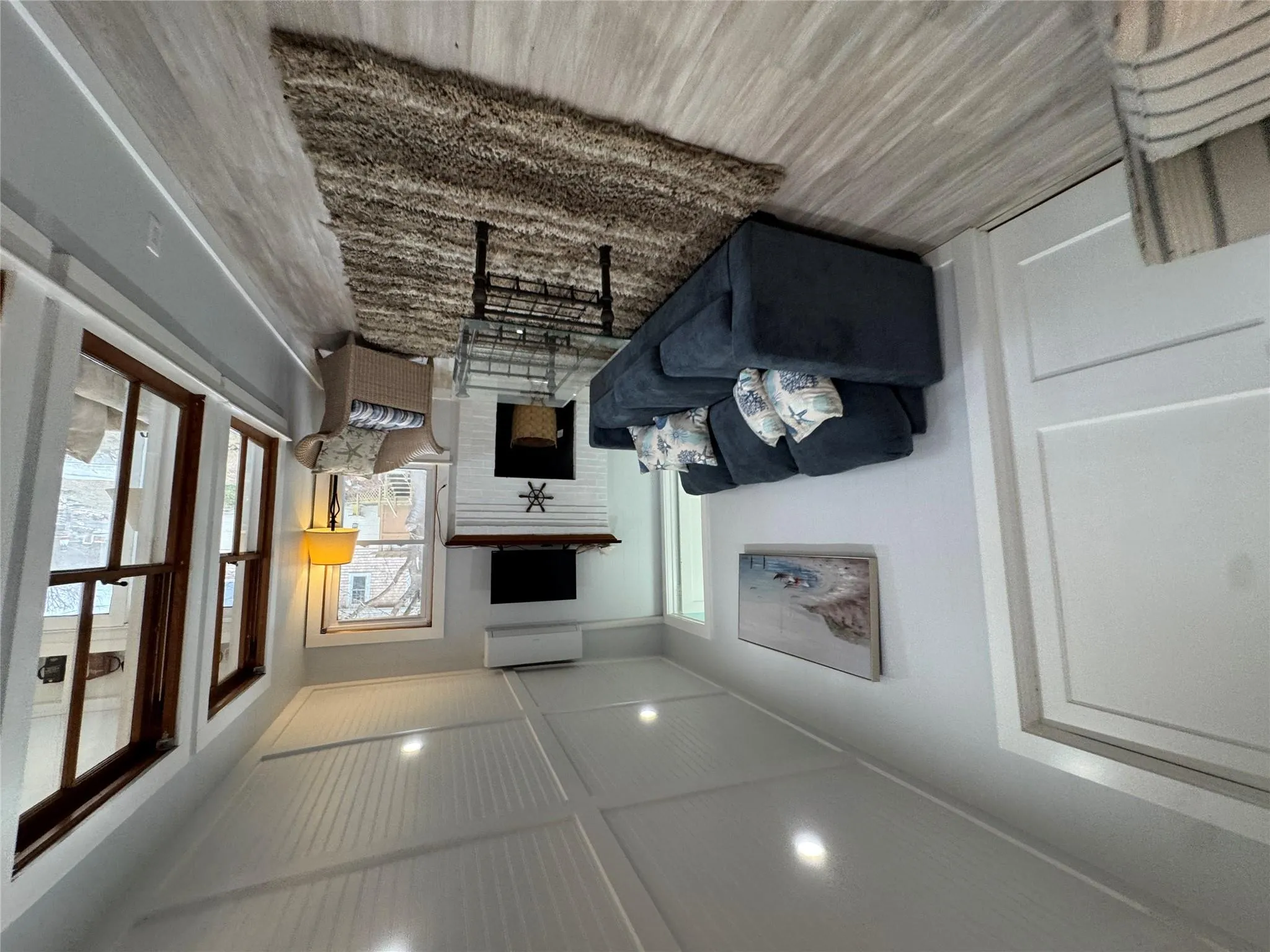 Living room with a brick fireplace, a wall unit AC, and light wood-type flooring Living room with a brick fireplace, a wall unit AC, and light wood-type flooring