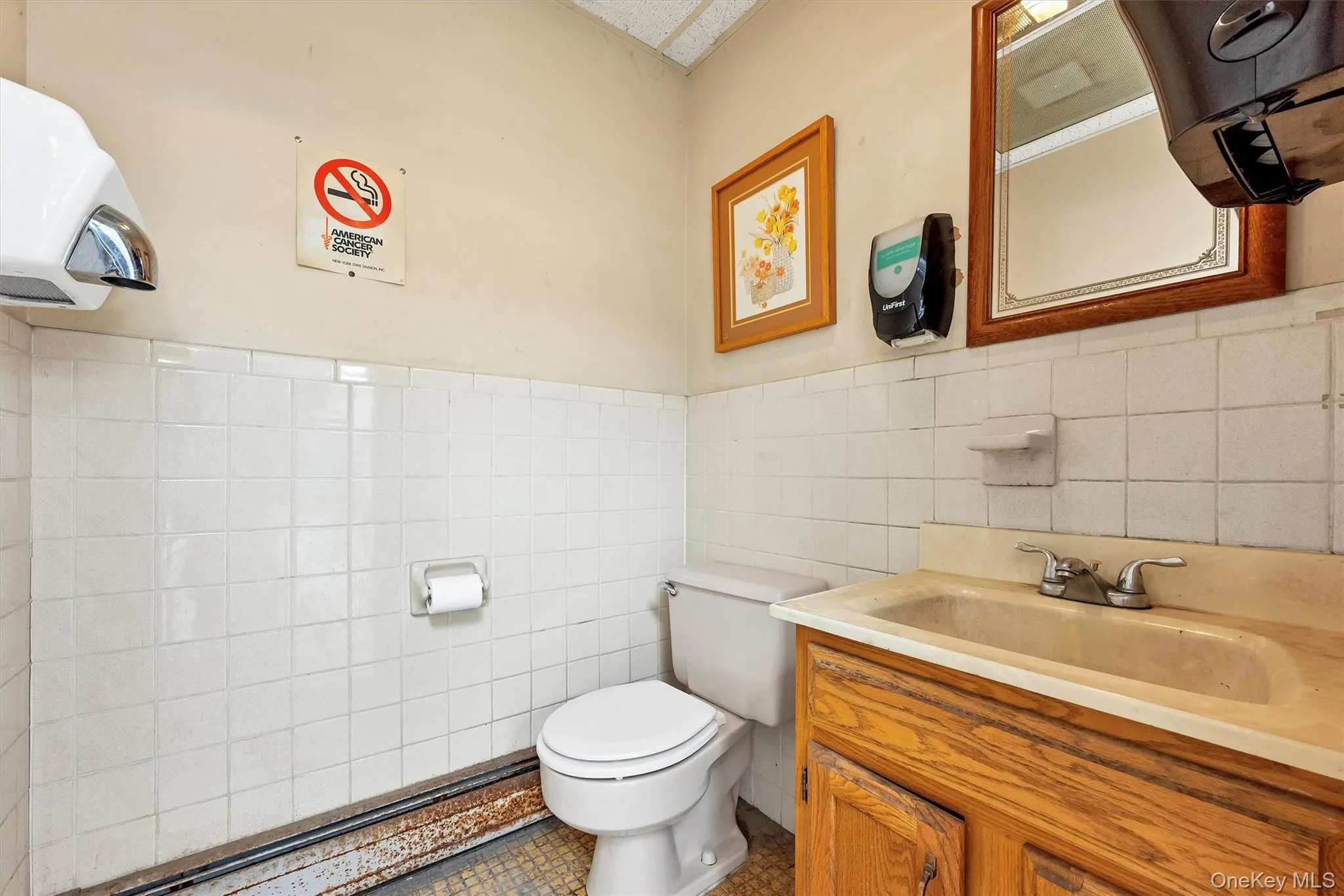 Bathroom with vanity, toilet, tile patterned flooring, and tile walls Bathroom with vanity, toilet, tile patterned flooring, and tile walls