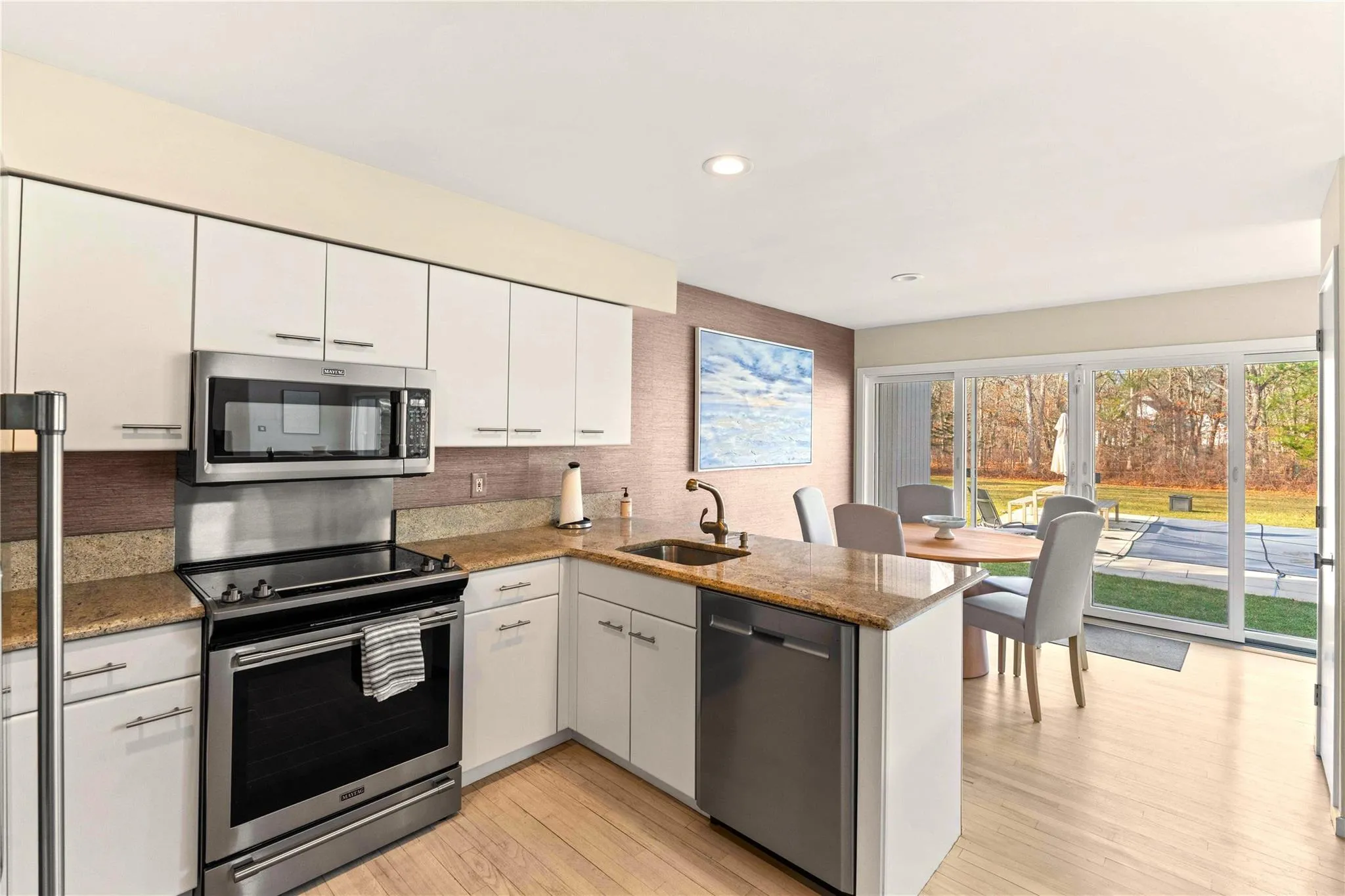 Kitchen featuring sink, white cabinets, light hardwood / wood-style floors, kitchen peninsula, and stainless steel appliances Kitchen featuring sink, white cabinets, light hardwood / wood-style floors, kitchen peninsula, and stainless steel appliances