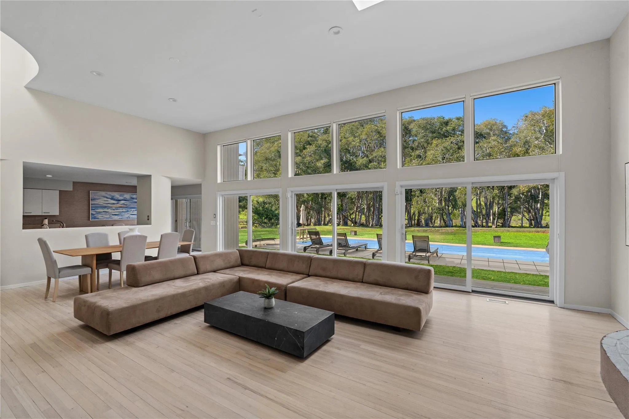 Great room with soaring ceilings , a healthy amount of sunlight, a towering ceiling, and light wood finished floors Great room with soaring ceilings , a healthy amount of sunlight, a towering ceiling, and light wood finished floors