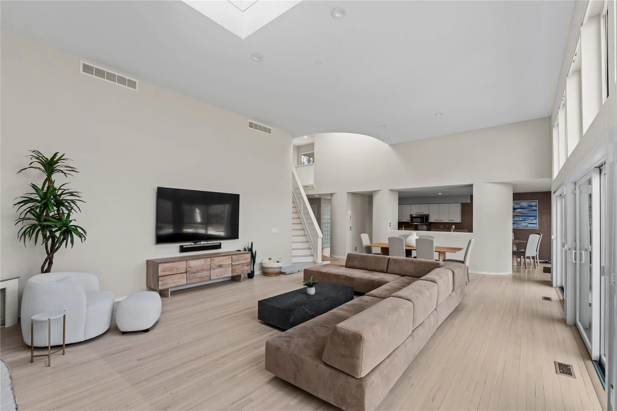 Living room featuring a towering ceiling, a skylight, and light wood-type flooring Living room featuring a towering ceiling, a skylight, and light wood-type flooring