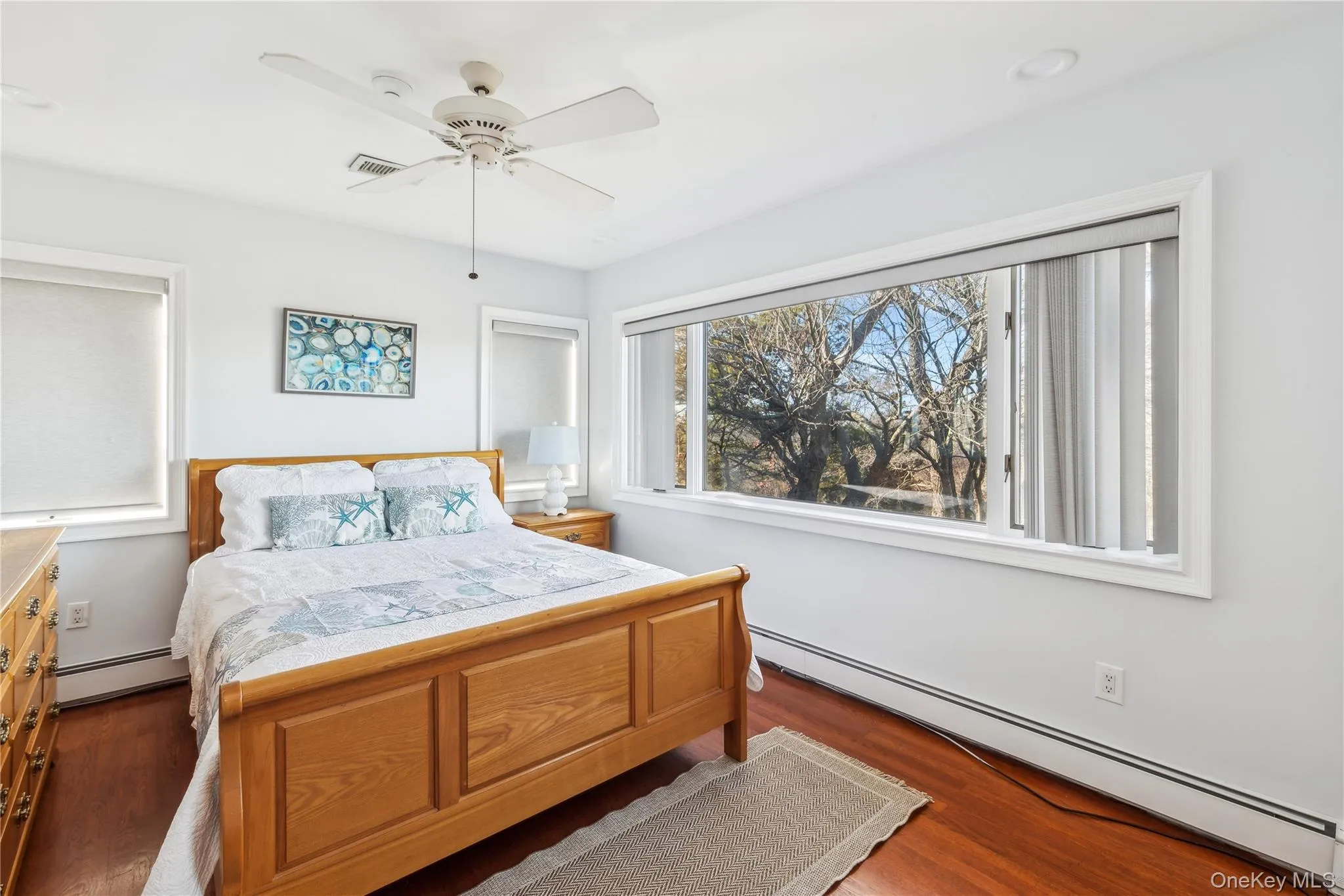 Bedroom with dark hardwood / wood-style flooring, a baseboard heating unit, and ceiling fan Bedroom with dark hardwood / wood-style flooring, a baseboard heating unit, and ceiling fan