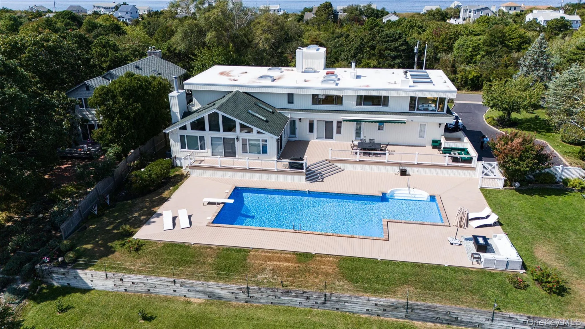 Rear view of property with a lawn, a fenced backyard, an outdoor pool, a chimney, and a patio area Rear view of property with a lawn, a fenced backyard, an outdoor pool, a chimney, and a patio area