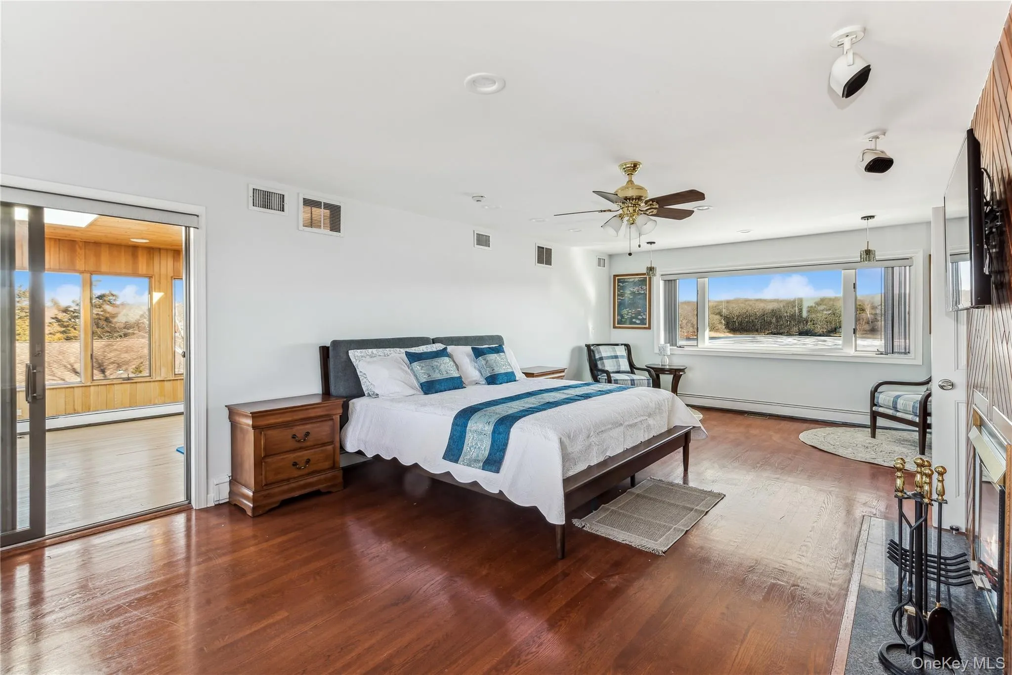 Bedroom with ceiling fan, wood-type flooring, and a baseboard heating unit Bedroom with ceiling fan, wood-type flooring, and a baseboard heating unit