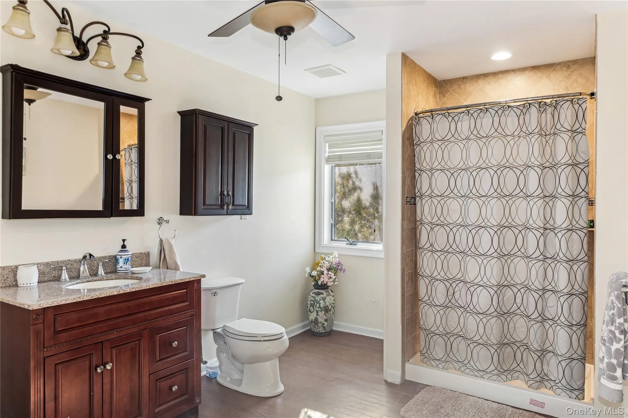Bathroom featuring hardwood / wood-style floors, curtained shower, vanity, ceiling fan, and toilet Bathroom featuring hardwood / wood-style floors, curtained shower, vanity, ceiling fan, and toilet