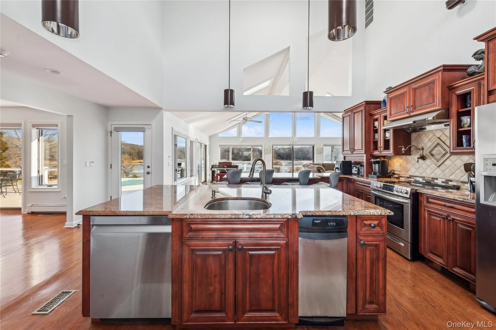 Kitchen with sink, an island with sink, pendant lighting, stainless steel appliances, and hardwood / wood-style floors Kitchen with sink, an island with sink, pendant lighting, stainless steel appliances, and hardwood / wood-style floors