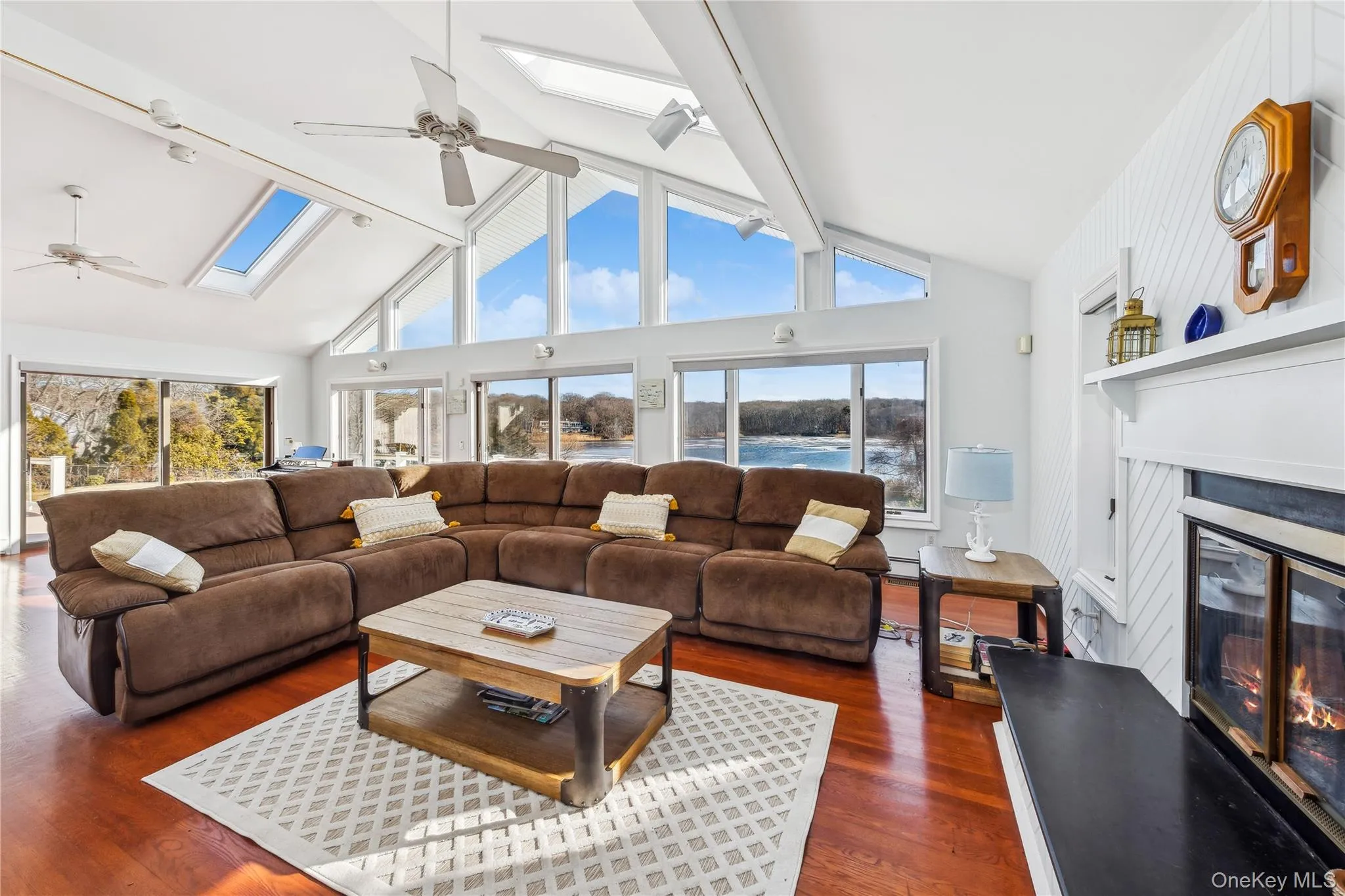 Living room with dark wood-type flooring, a skylight, ceiling fan, and a water view Living room with dark wood-type flooring, a skylight, ceiling fan, and a water view