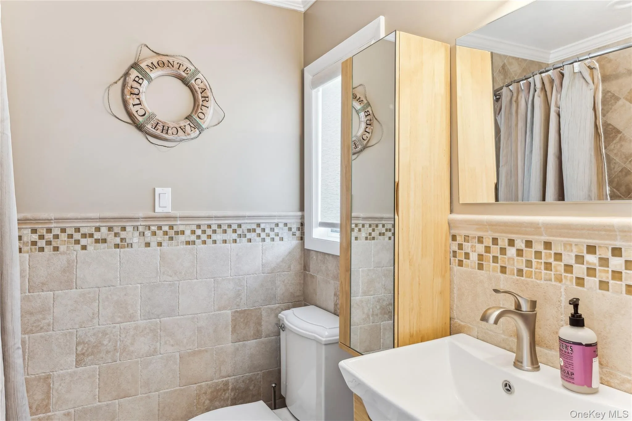 Bathroom featuring sink, tile walls, toilet, crown molding, and a shower with shower curtain Bathroom featuring sink, tile walls, toilet, crown molding, and a shower with shower curtain