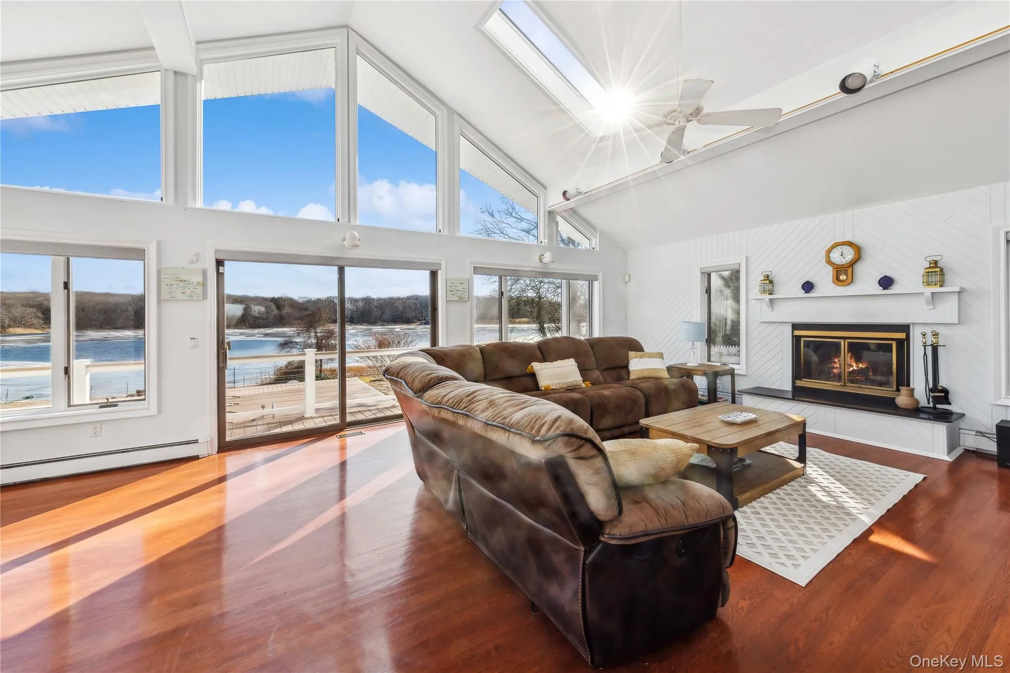 Living room with a water view, high vaulted ceiling, dark hardwood / wood-style flooring, and baseboard heating Living room with a water view, high vaulted ceiling, dark hardwood / wood-style flooring, and baseboard heating