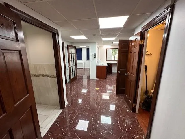 Corridor featuring radiator heating unit and a drop ceiling Corridor featuring radiator heating unit and a drop ceiling