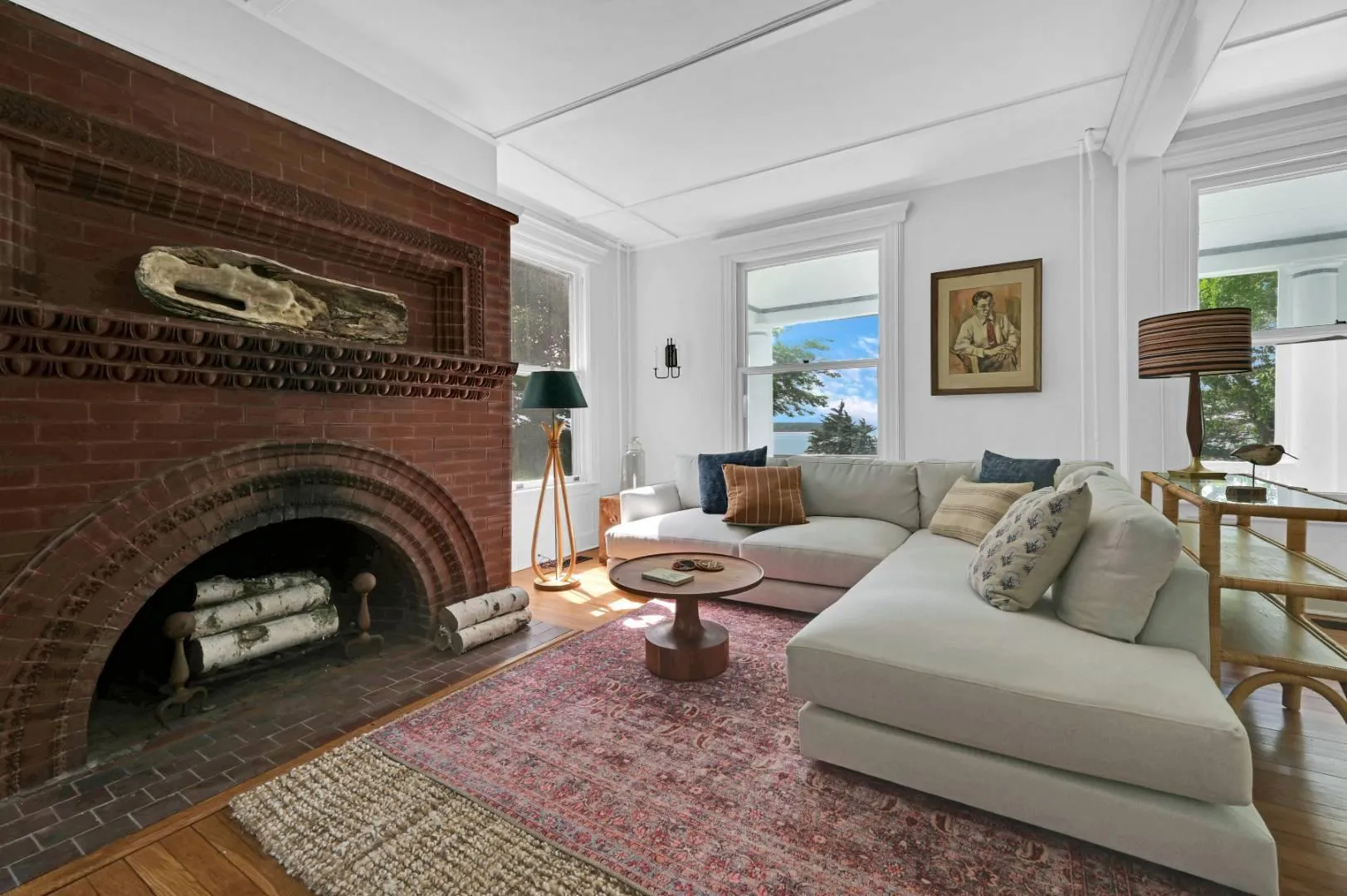 Living room featuring a brick fireplace, dark wood-type flooring, and a healthy amount of sunlight Living room featuring a brick fireplace, dark wood-type flooring, and a healthy amount of sunlight