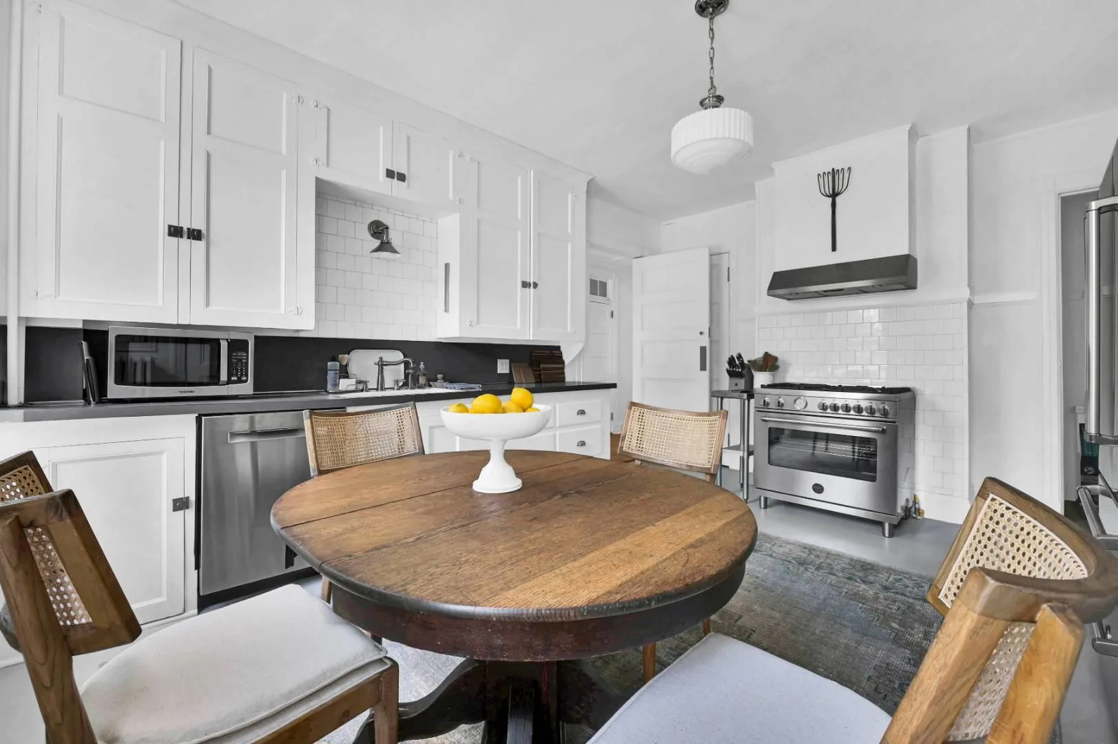 Kitchen with white cabinetry, appliances with stainless steel finishes, tasteful backsplash, and exhaust hood Kitchen with white cabinetry, appliances with stainless steel finishes, tasteful backsplash, and exhaust hood