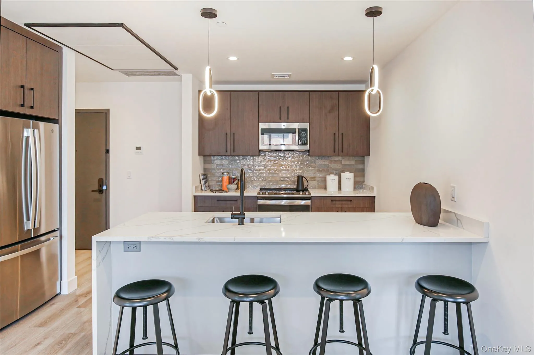 Kitchen featuring sink, appliances with stainless steel finishes, backsplash, light stone counters, and kitchen peninsula Kitchen featuring sink, appliances with stainless steel finishes, backsplash, light stone counters, and kitchen peninsula