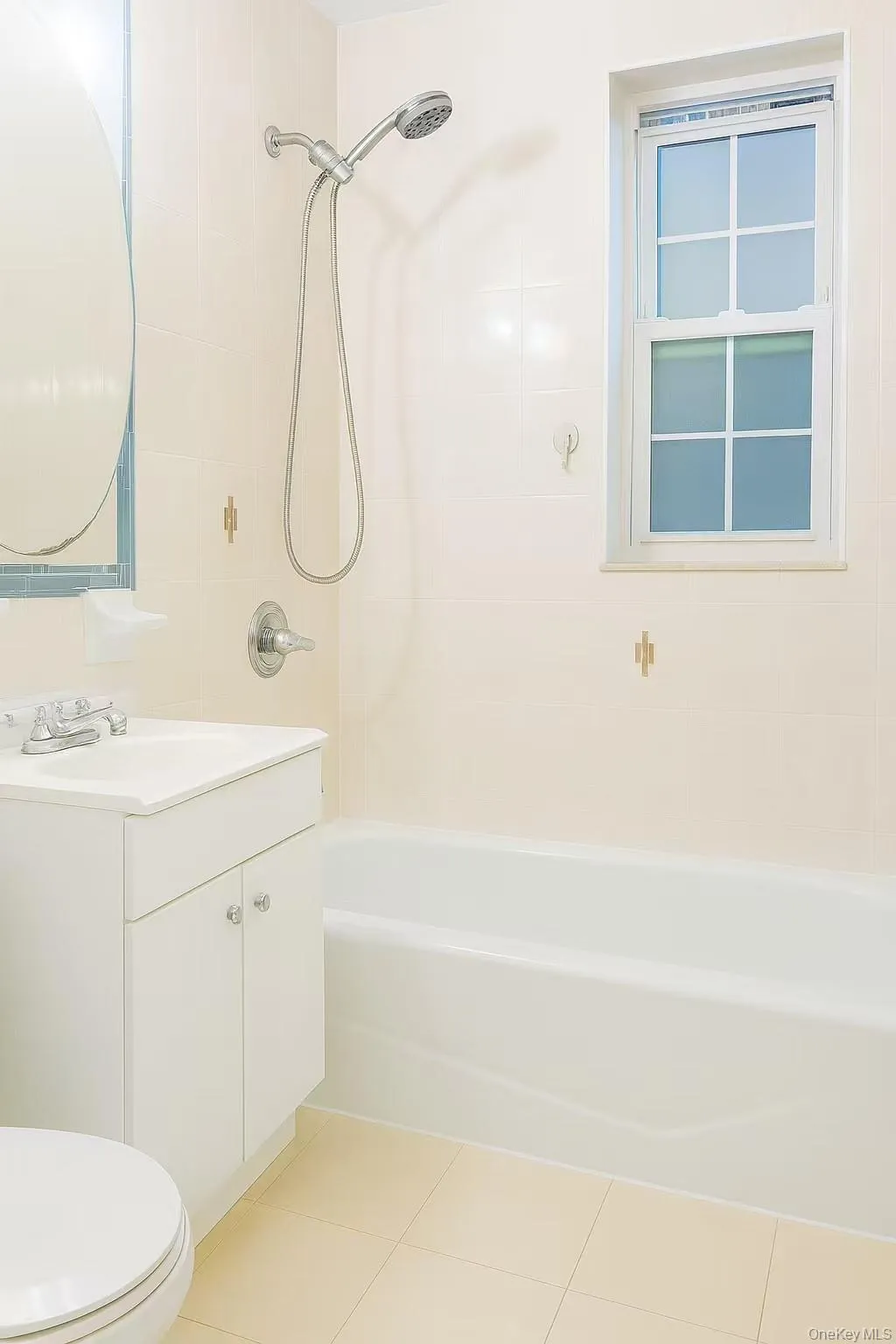 Bathroom featuring vanity, light tile patterned floors, and washtub / shower combination Bathroom featuring vanity, light tile patterned floors, and washtub / shower combination