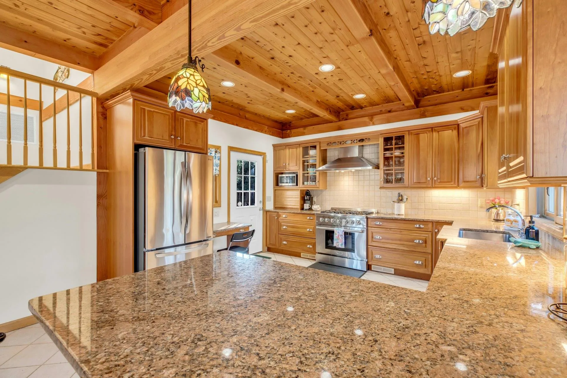 Kitchen featuring stone countertops, sink, backsplash, stainless steel appliances, and wall chimney exhaust hood Kitchen featuring stone countertops, sink, backsplash, stainless steel appliances, and wall chimney exhaust hood