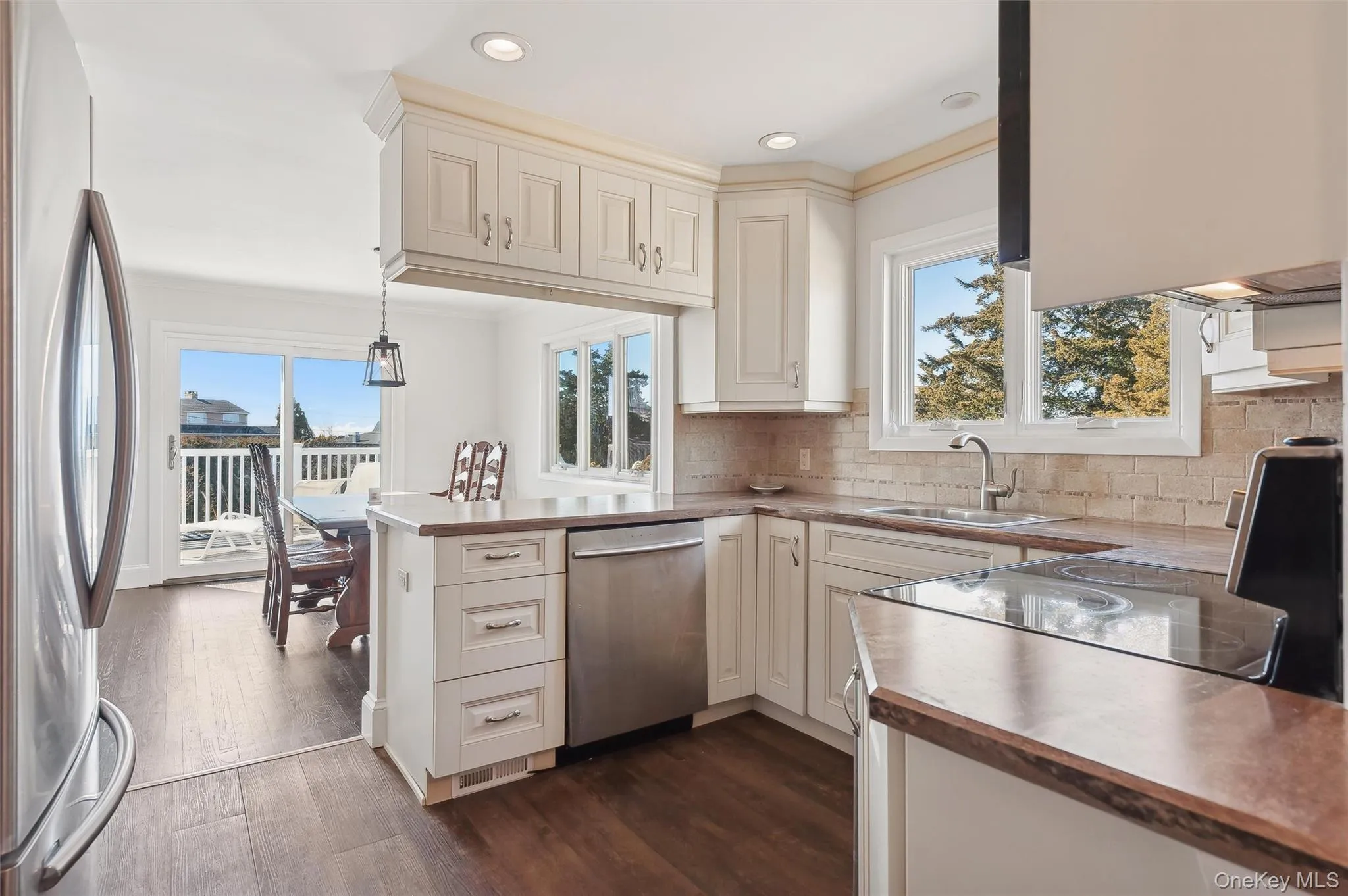 Kitchen featuring butcher block countertops, sink, hanging light fixtures, kitchen peninsula, and stainless steel appliances Kitchen featuring butcher block countertops, sink, hanging light fixtures, kitchen peninsula, and stainless steel appliances