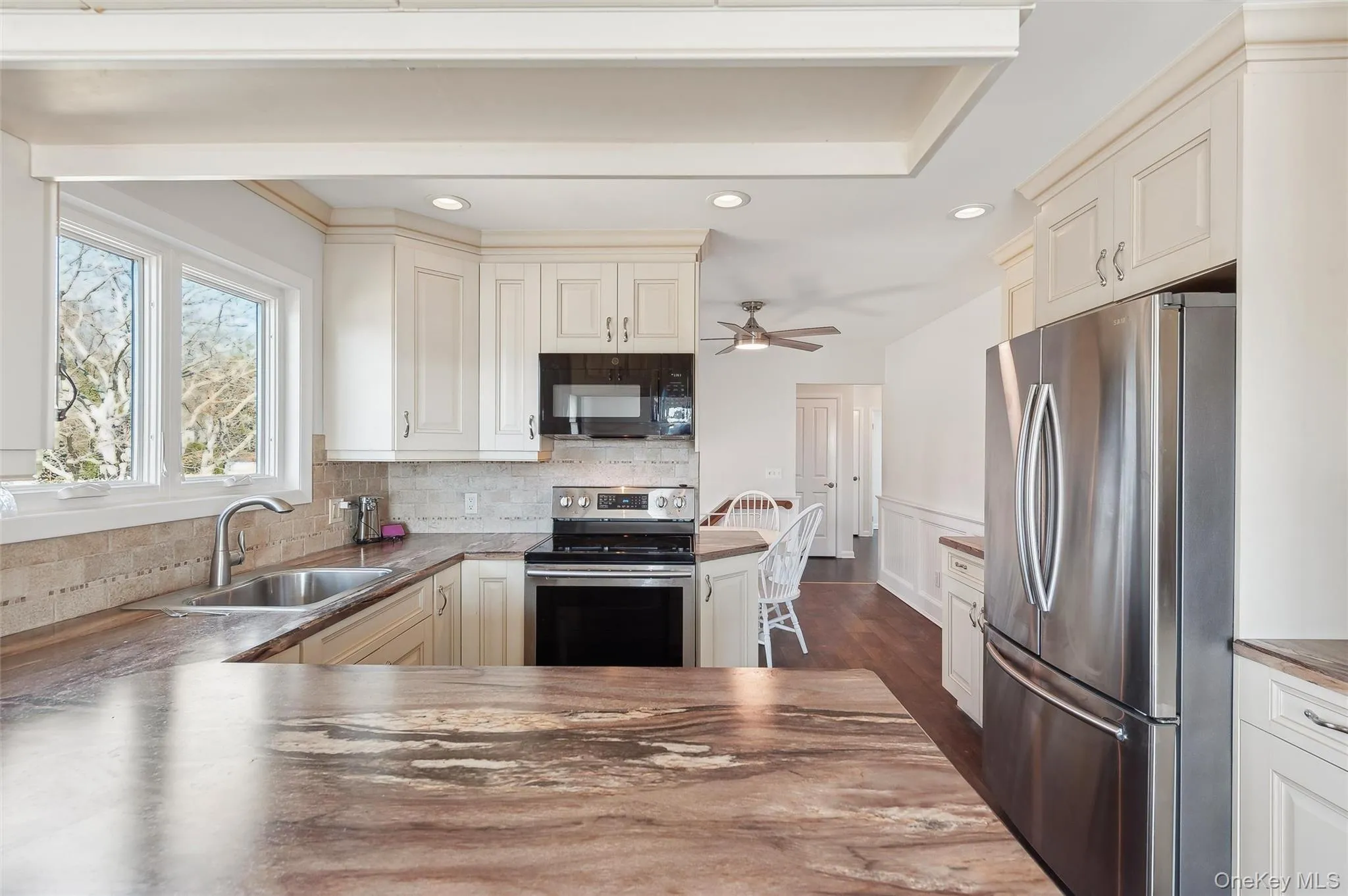 Kitchen featuring appliances with stainless steel finishes, dark hardwood / wood-style floors, sink, backsplash, and kitchen peninsula Kitchen featuring appliances with stainless steel finishes, dark hardwood / wood-style floors, sink, backsplash, and kitchen peninsula