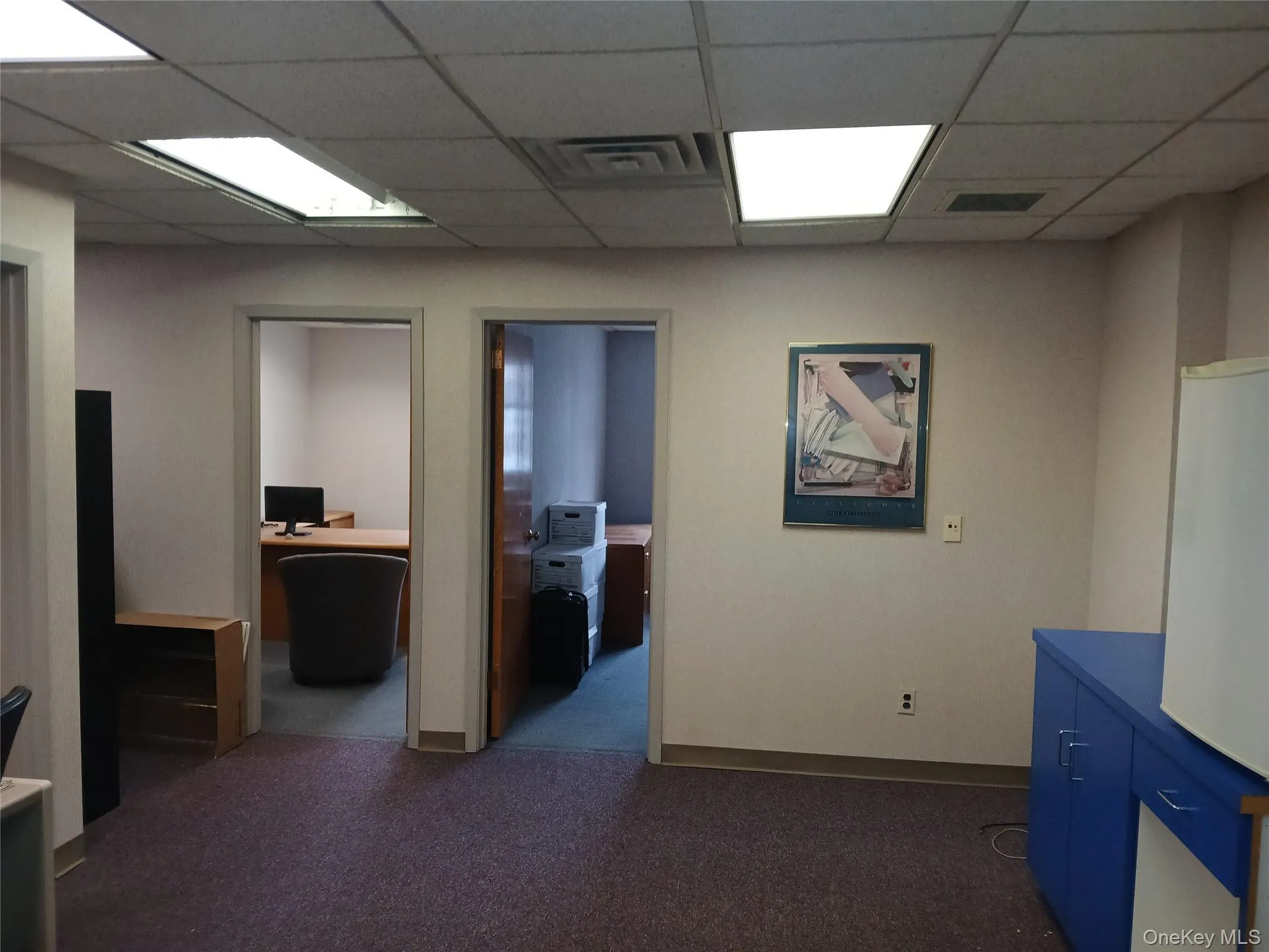 Hallway with dark colored carpet and a paneled ceiling Hallway with dark colored carpet and a paneled ceiling