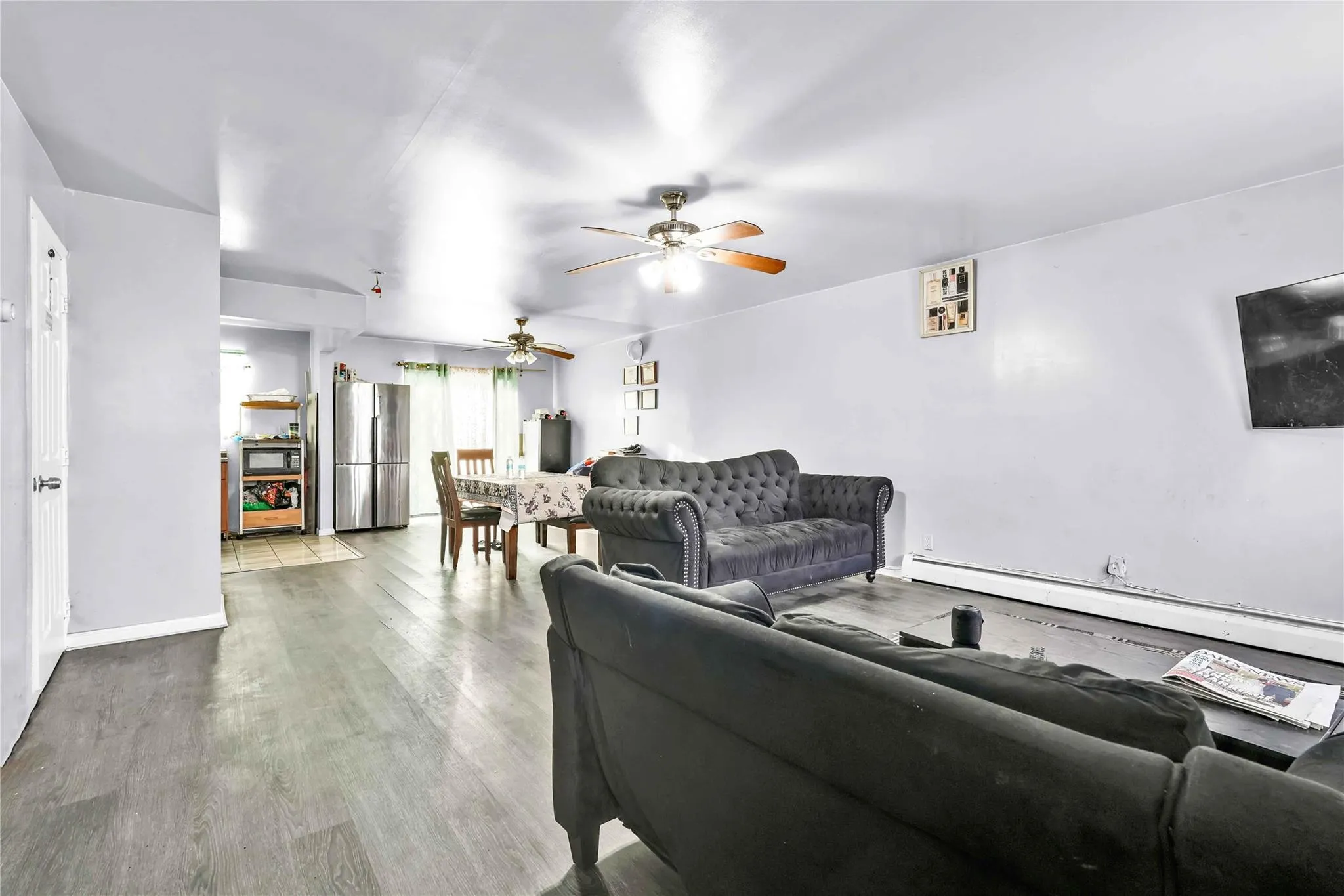 Living room featuring hardwood / wood-style flooring, a baseboard radiator, and ceiling fan Living room featuring hardwood / wood-style flooring, a baseboard radiator, and ceiling fan