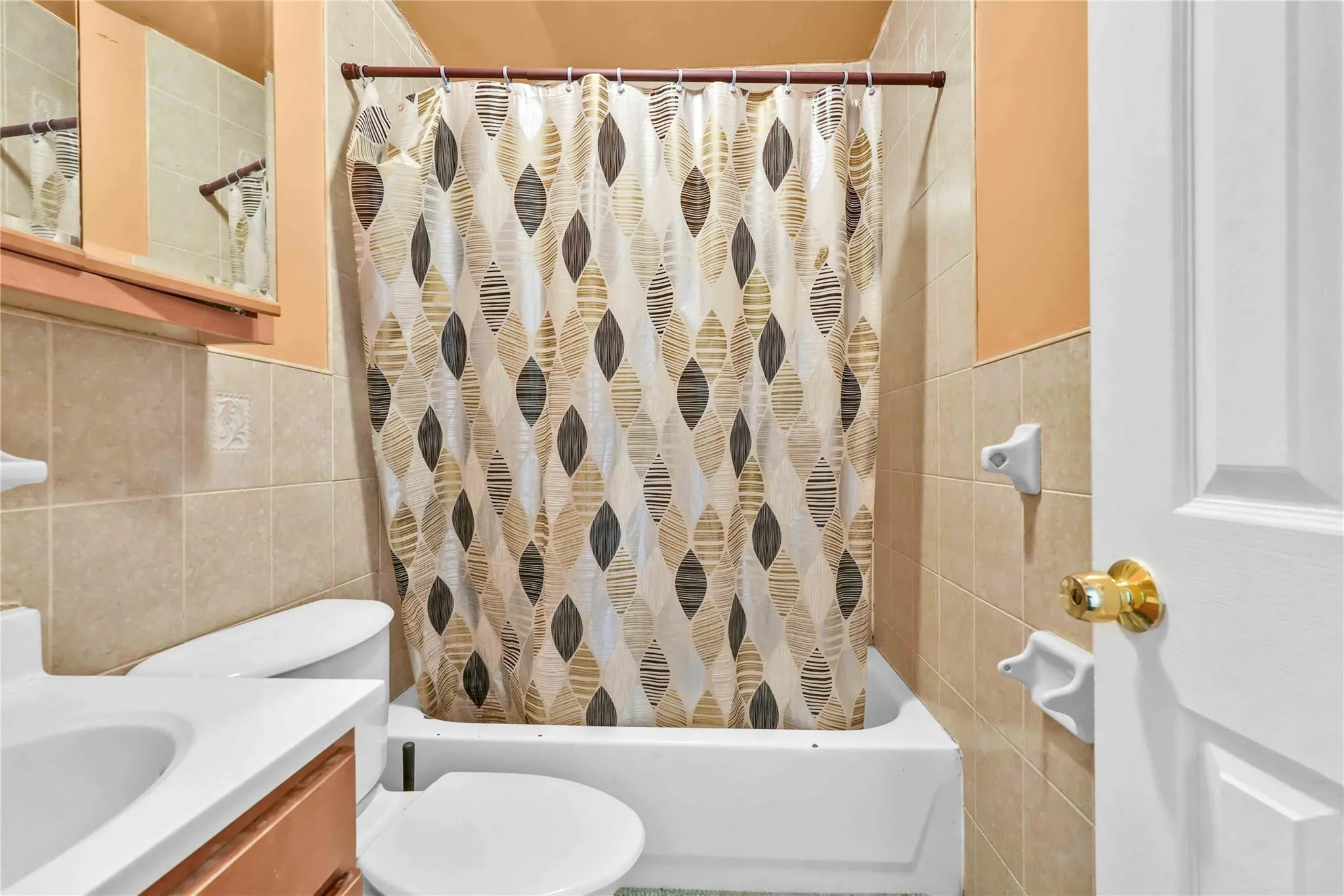 Full bathroom with shower / tub combo with curtain, vanity, toilet, and tile walls Full bathroom with shower / tub combo with curtain, vanity, toilet, and tile walls