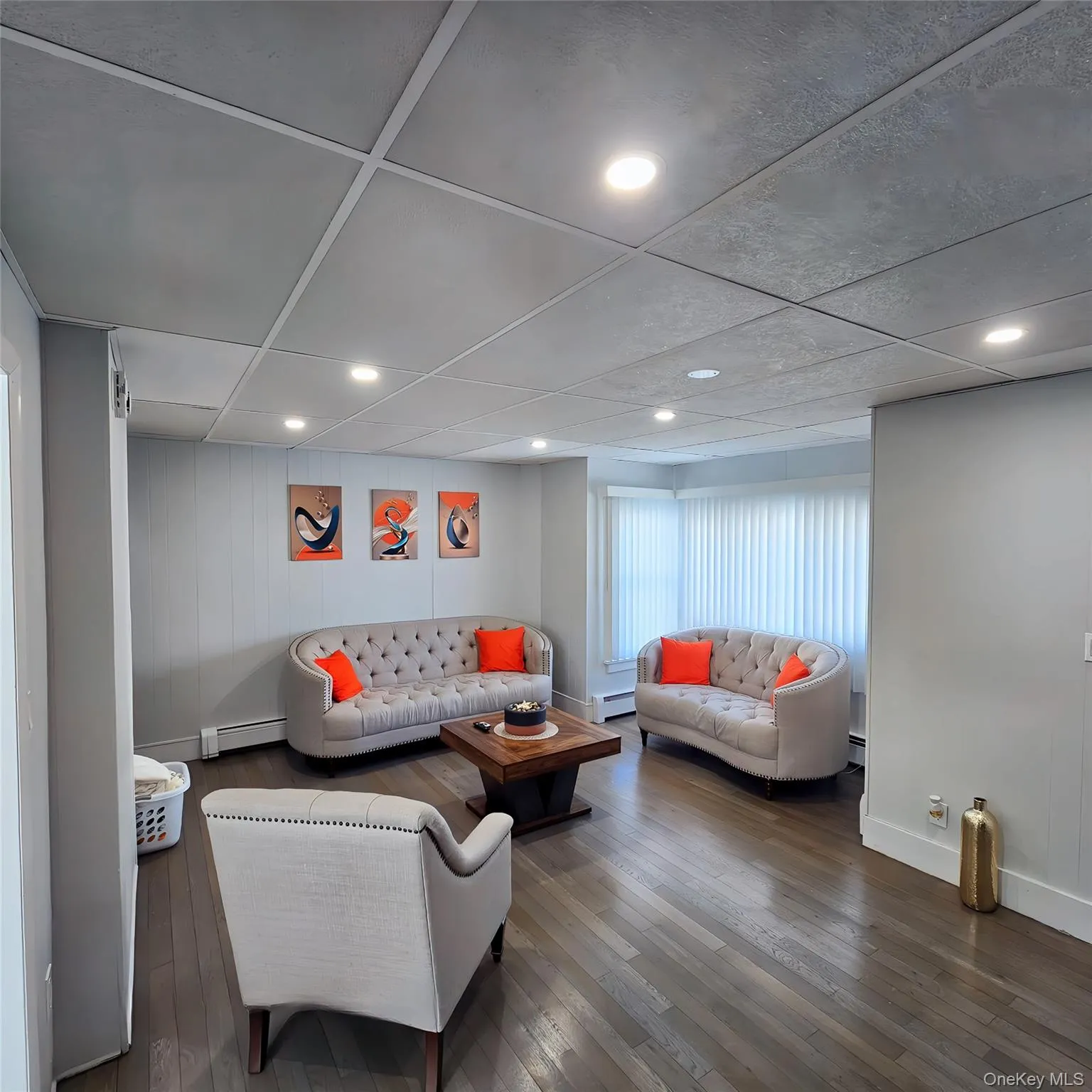 Living room featuring a baseboard heating unit, baseboards, and hardwood / wood-style floors Living room featuring a baseboard heating unit, baseboards, and hardwood / wood-style floors