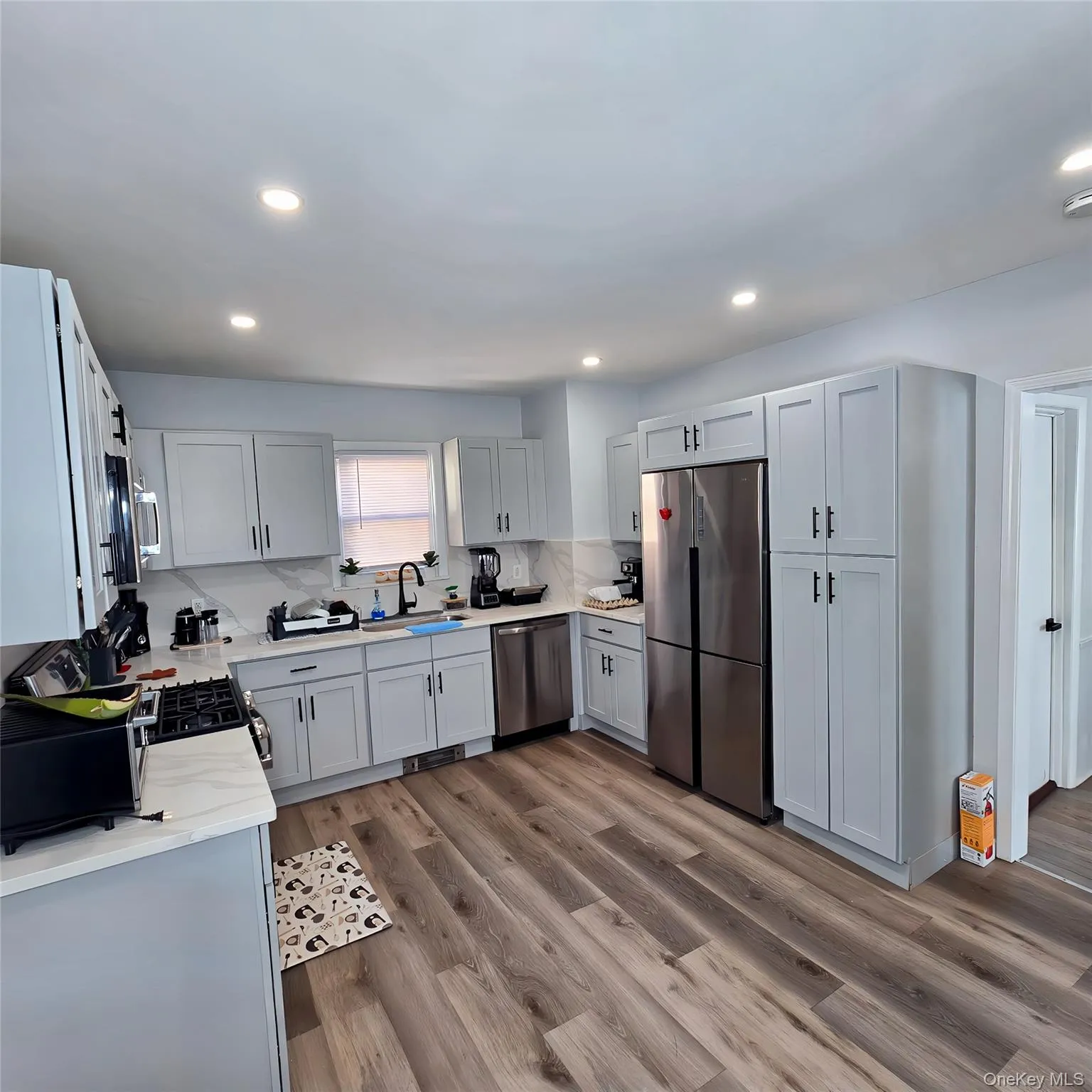 Kitchen featuring recessed lighting, wood finished floors, a sink, appliances with stainless steel finishes, and decorative backsplash Kitchen featuring recessed lighting, wood finished floors, a sink, appliances with stainless steel finishes, and decorative backsplash