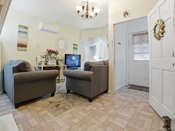 Living area with brick patterned floors, a chandelier, healthy amount of natural light, a wall mounted air conditioner, and crown molding Living area with brick patterned floors, a chandelier, healthy amount of natural light, a wall mounted air conditioner, and crown molding