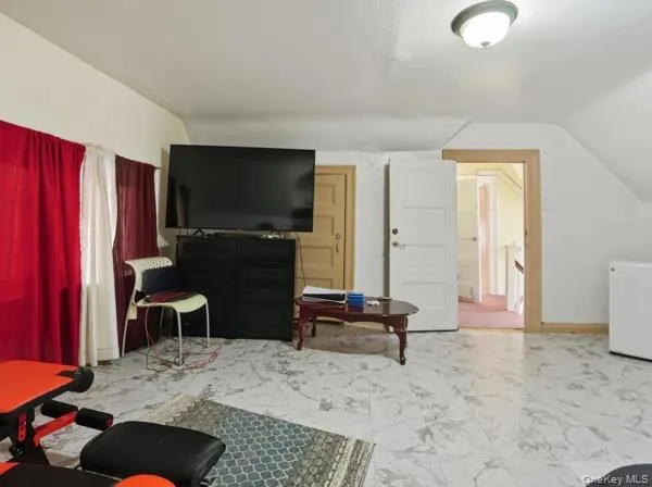 Living area featuring marble look tile flooring and lofted ceiling Living area featuring marble look tile flooring and lofted ceiling