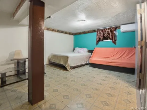 Bedroom featuring a textured ceiling and an AC wall unit Bedroom featuring a textured ceiling and an AC wall unit