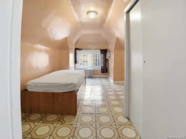 Bedroom with lofted ceiling, radiator, and a closet Bedroom with lofted ceiling, radiator, and a closet