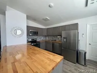 Kitchen featuring tasteful backsplash, butcher block countertops, stainless steel appliances, and light wood-style flooring Kitchen featuring tasteful backsplash, butcher block countertops, stainless steel appliances, and light wood-style flooring