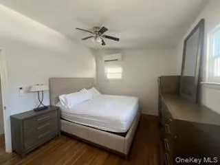 Bedroom with dark wood-style flooring, a wall unit AC, and ceiling fan Bedroom with dark wood-style flooring, a wall unit AC, and ceiling fan