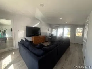 Living room with light wood finished floors and a wall mounted air conditioner Living room with light wood finished floors and a wall mounted air conditioner